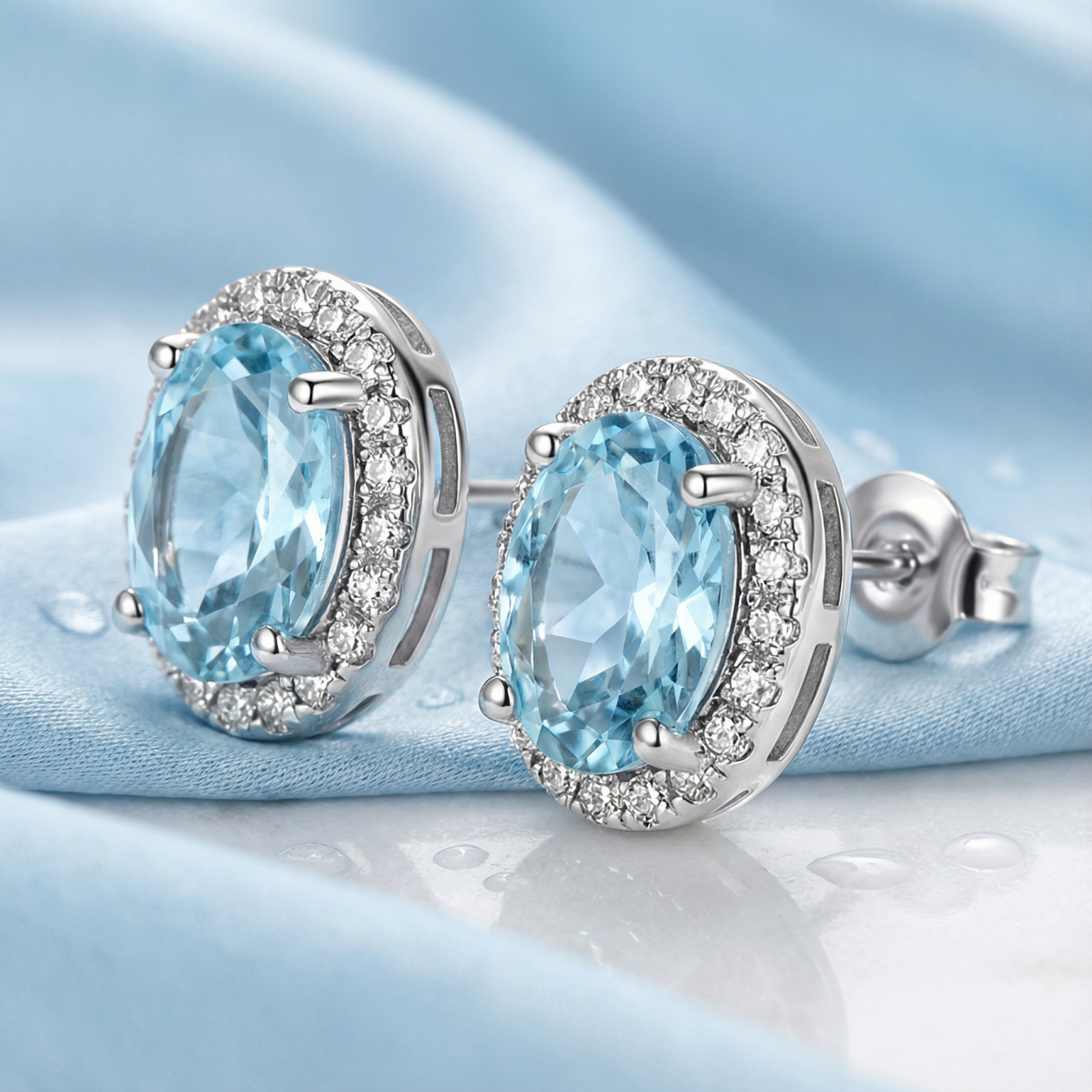 Macro view of oval simulated aquamarine halo stud earrings in sterling silver showing the side profile and setting.