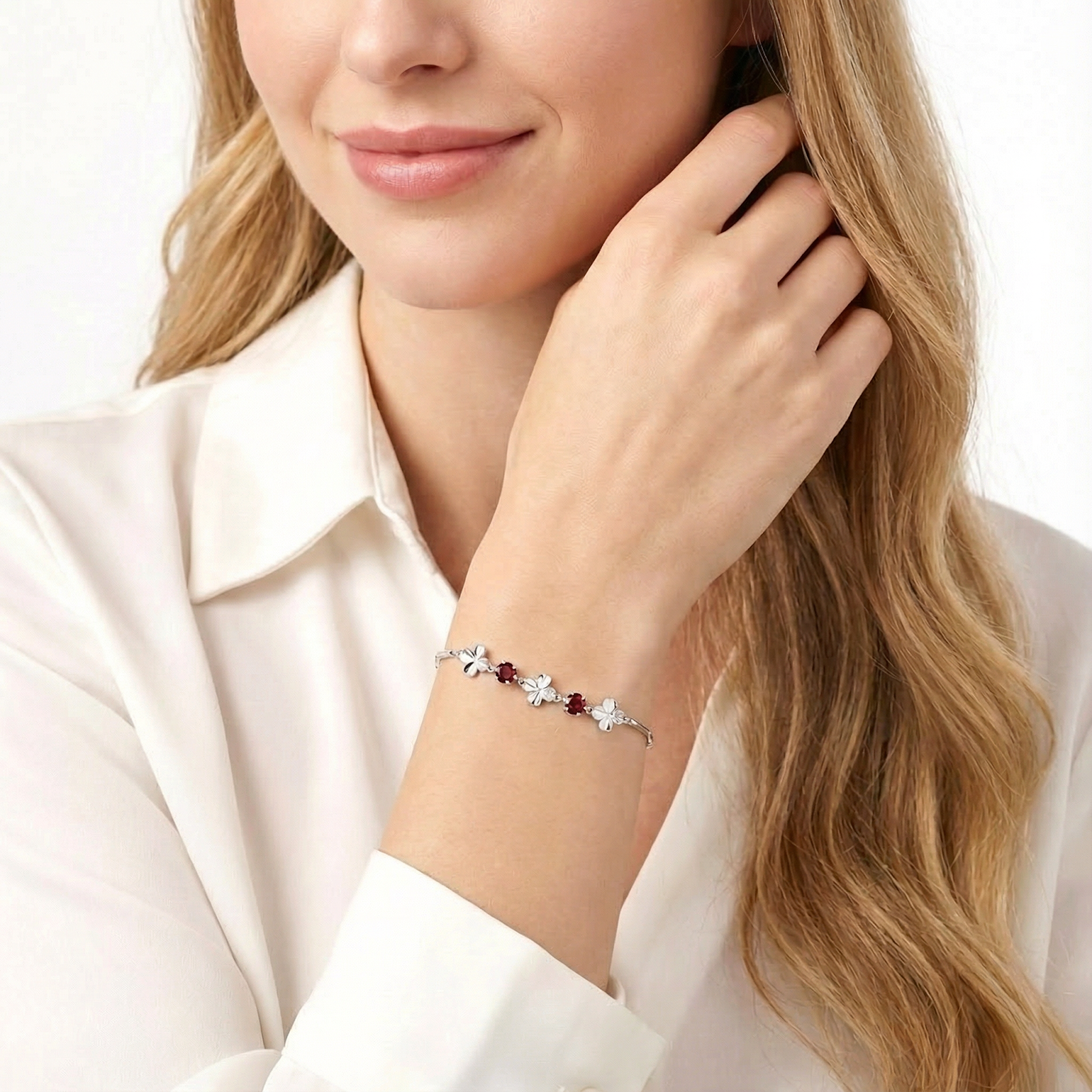 Woman wearing the sterling silver Celandine clover bracelet with red simulated garnets on her wrist.