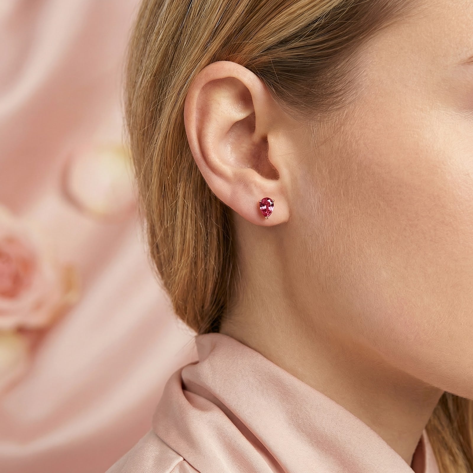 Model wearing a pear-cut simulated pink tourmaline stud earring in 18K gold vermeil.