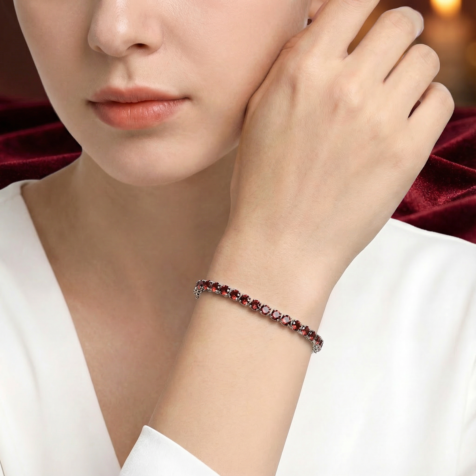 Stainless steel January birthstone tennis bracelet with red simulated garnets worn by a model.