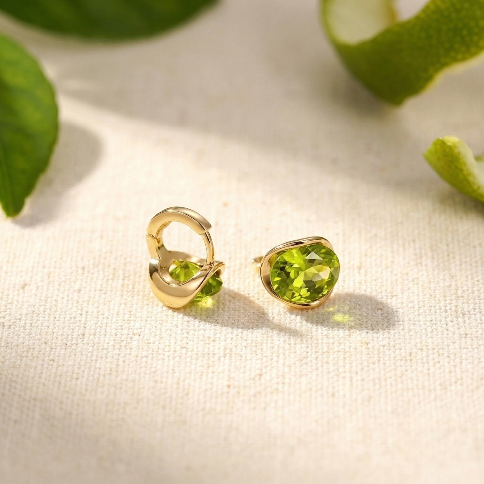 Detail view of 18K gold vermeil oval peridot earrings showing the front stone and the hinged clasp design.
