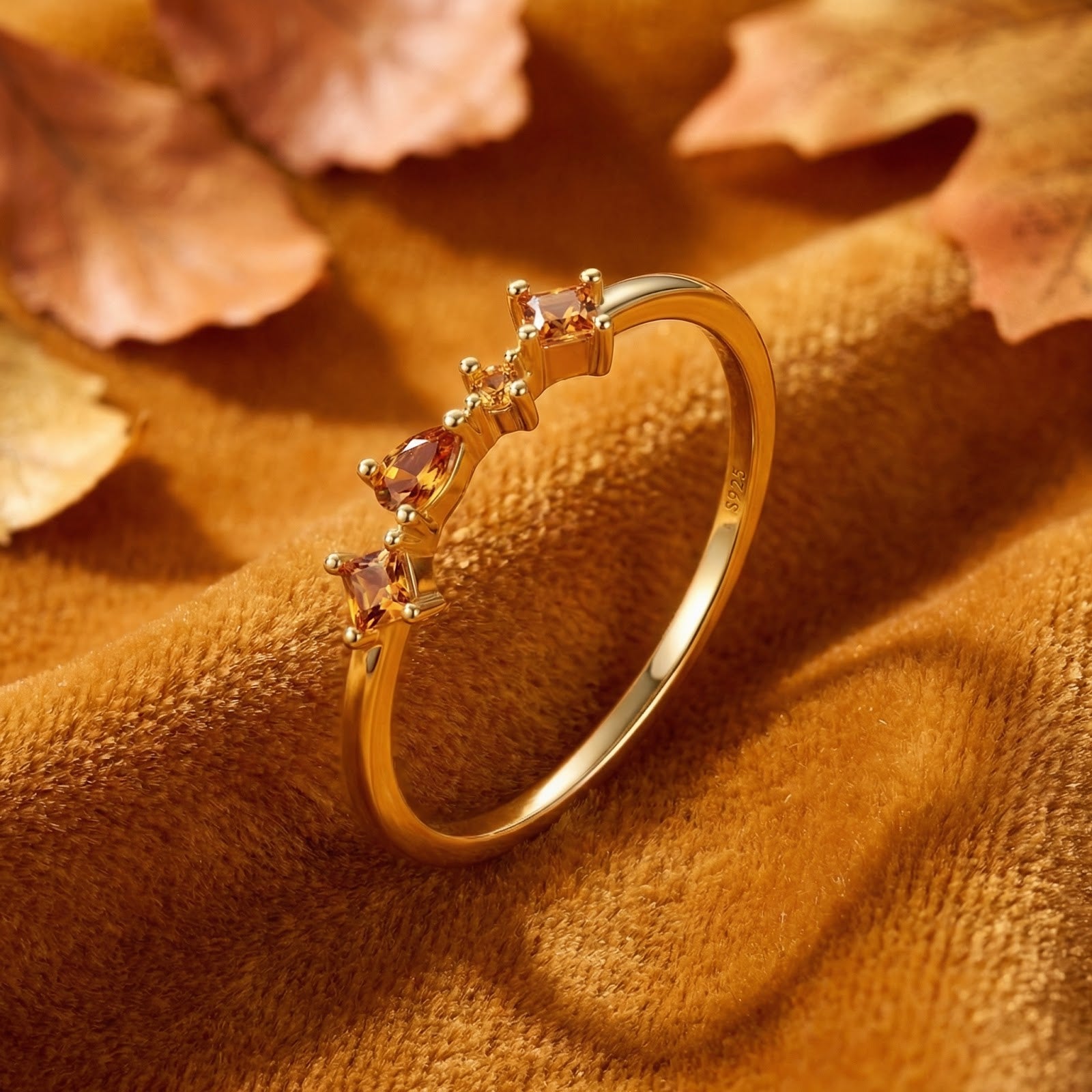 18K gold vermeil Kalisara Row ring with honeyed simulated topaz stones on a textured autumn leaf background.