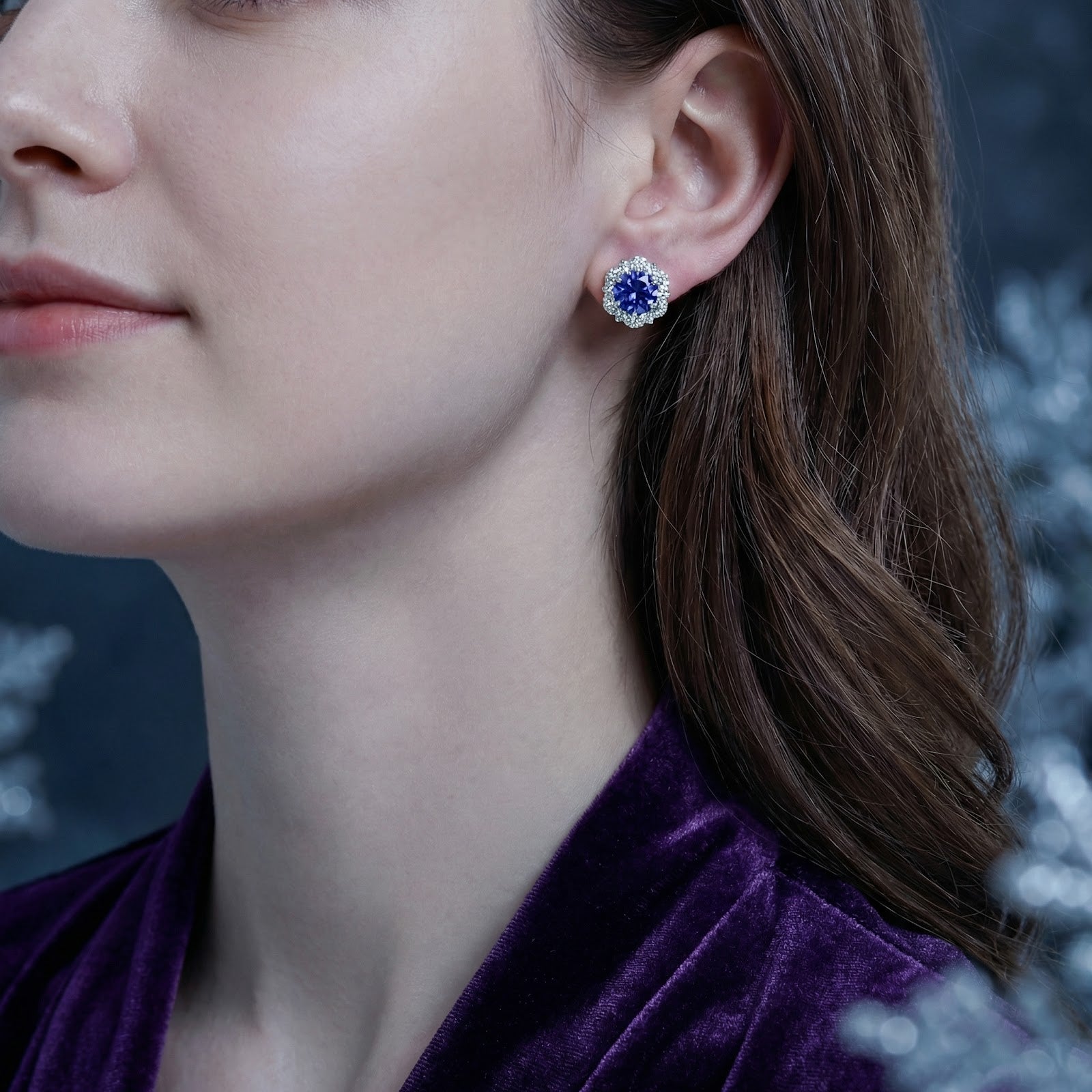 Model wearing the Sidraea Blossom sterling silver and simulated tanzanite halo stud earring with a purple velvet top.