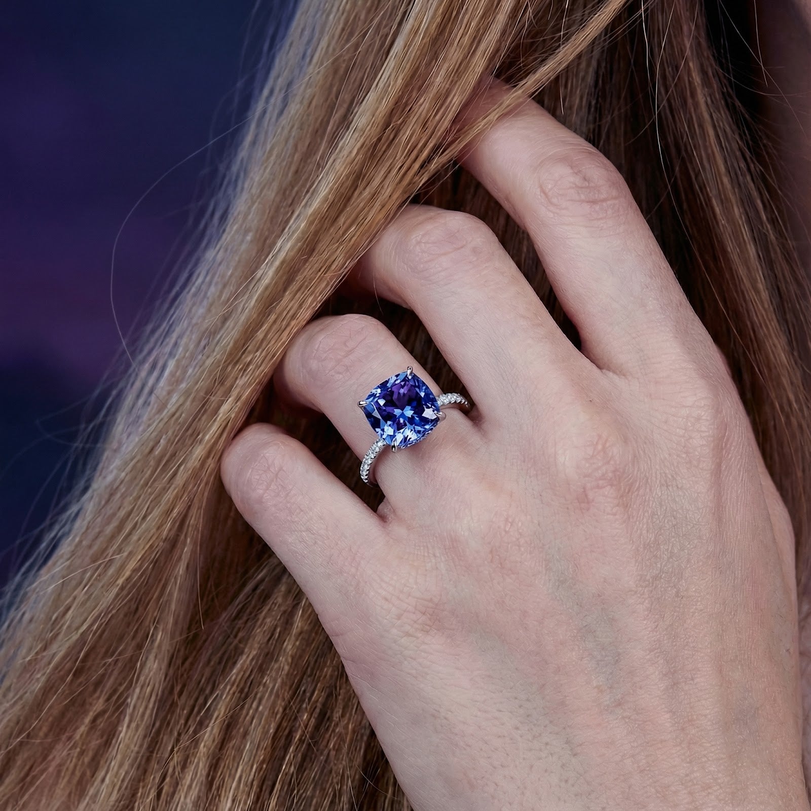 Close-up of the cushion-cut simulated tanzanite S925 sterling silver ring on a model's hand.