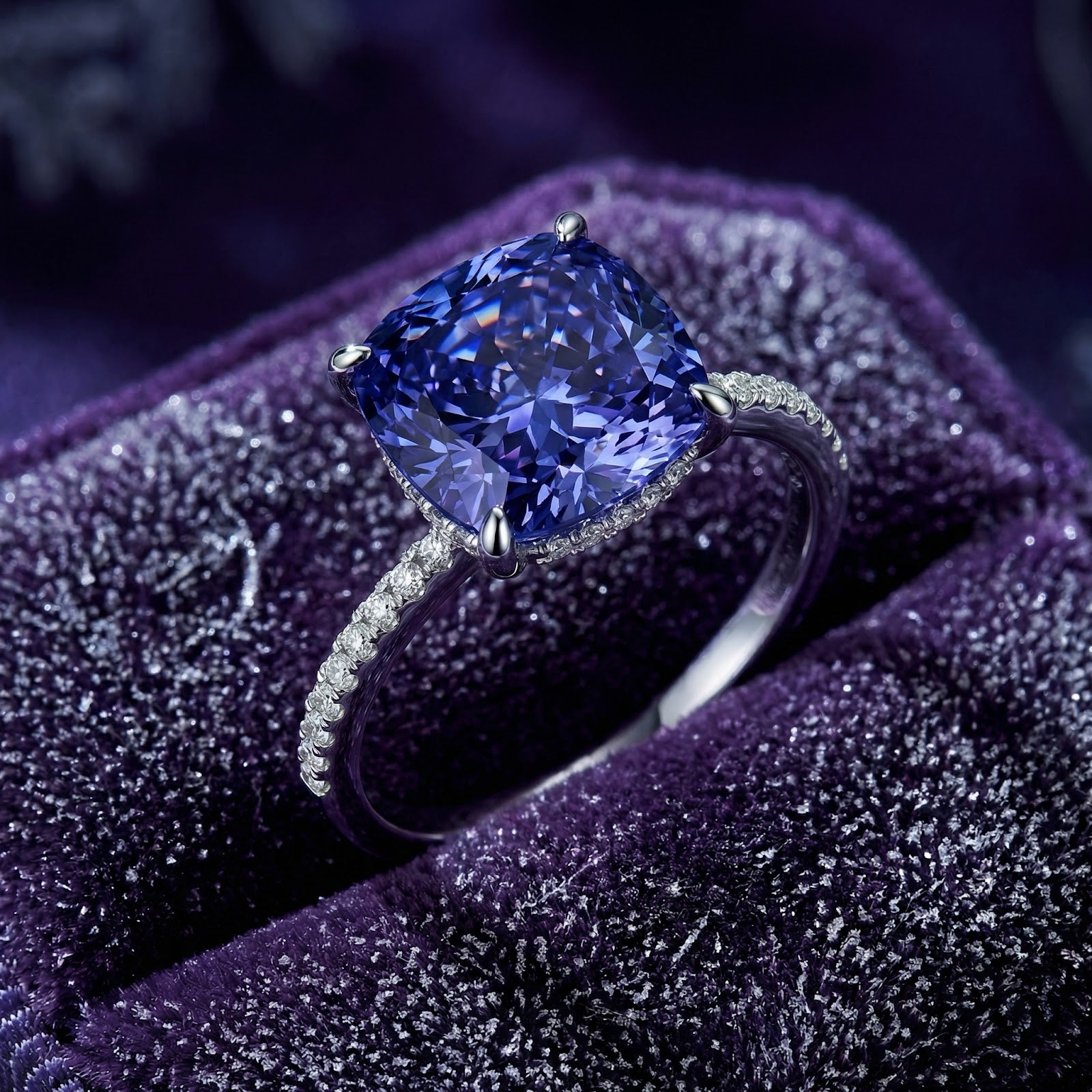 Cushion-cut simulated tanzanite ring in S925 sterling silver with pavé band on purple velvet.