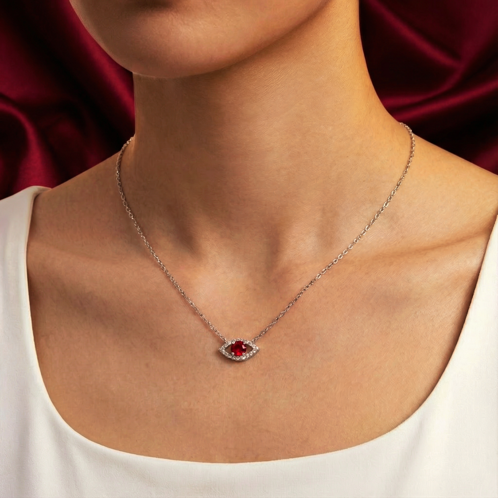 Sterling silver Alarice Eye necklace with a red moissanite pendant worn on a model's neck.
