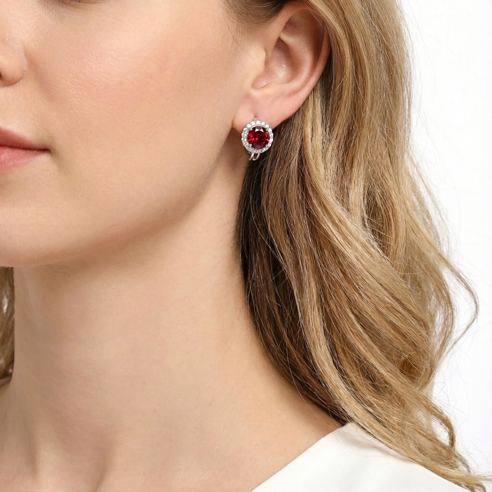 Side profile of a woman wearing a silver halo stud earring with a brilliant red ruby.