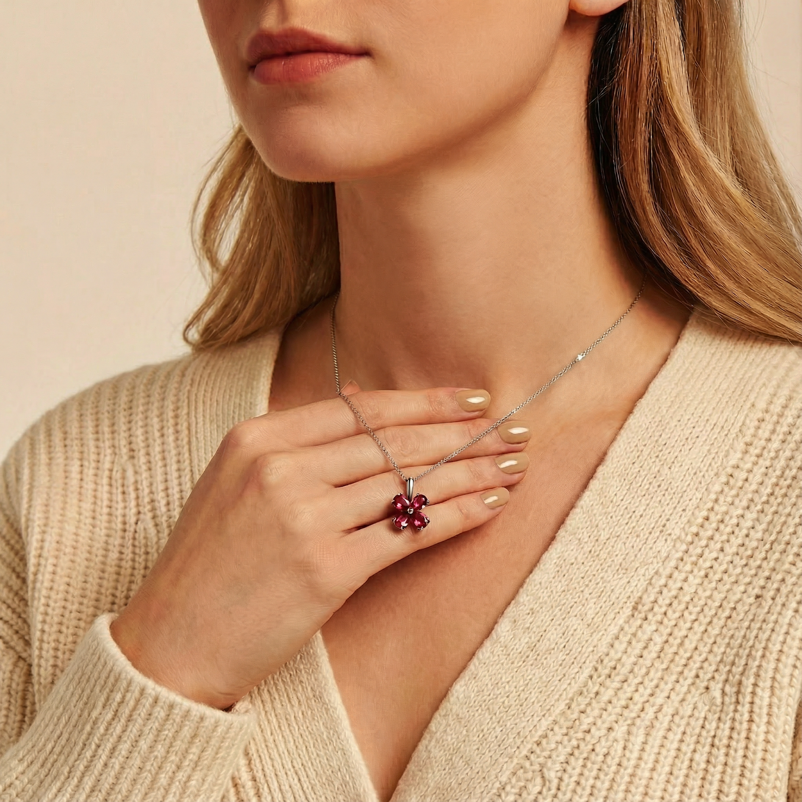 Sterling silver floral necklace with pear-cut simulated rubies held against skin to show product scale.