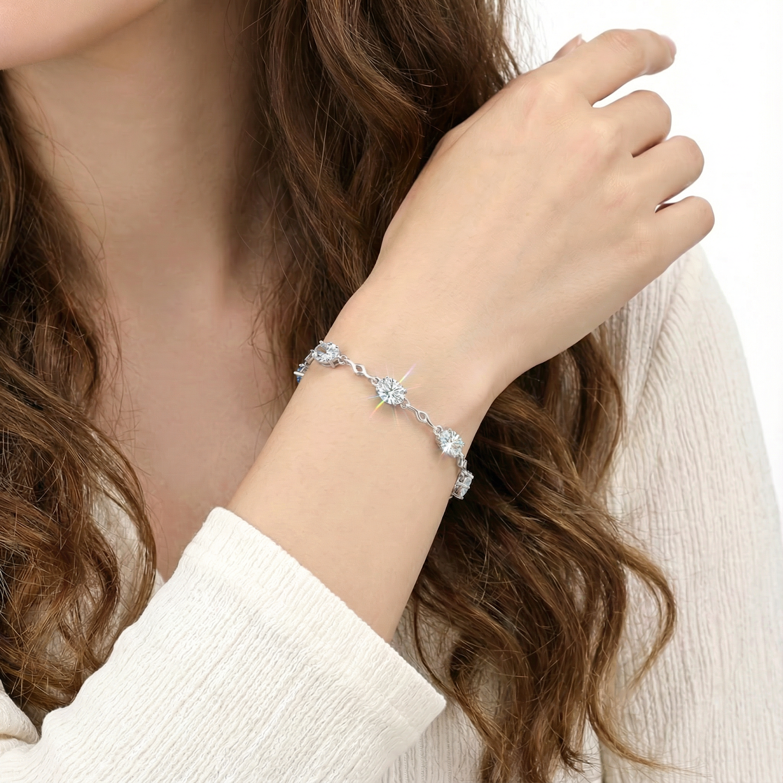 Sterling silver station bracelet with oval zirconia stones worn on a woman's wrist.
