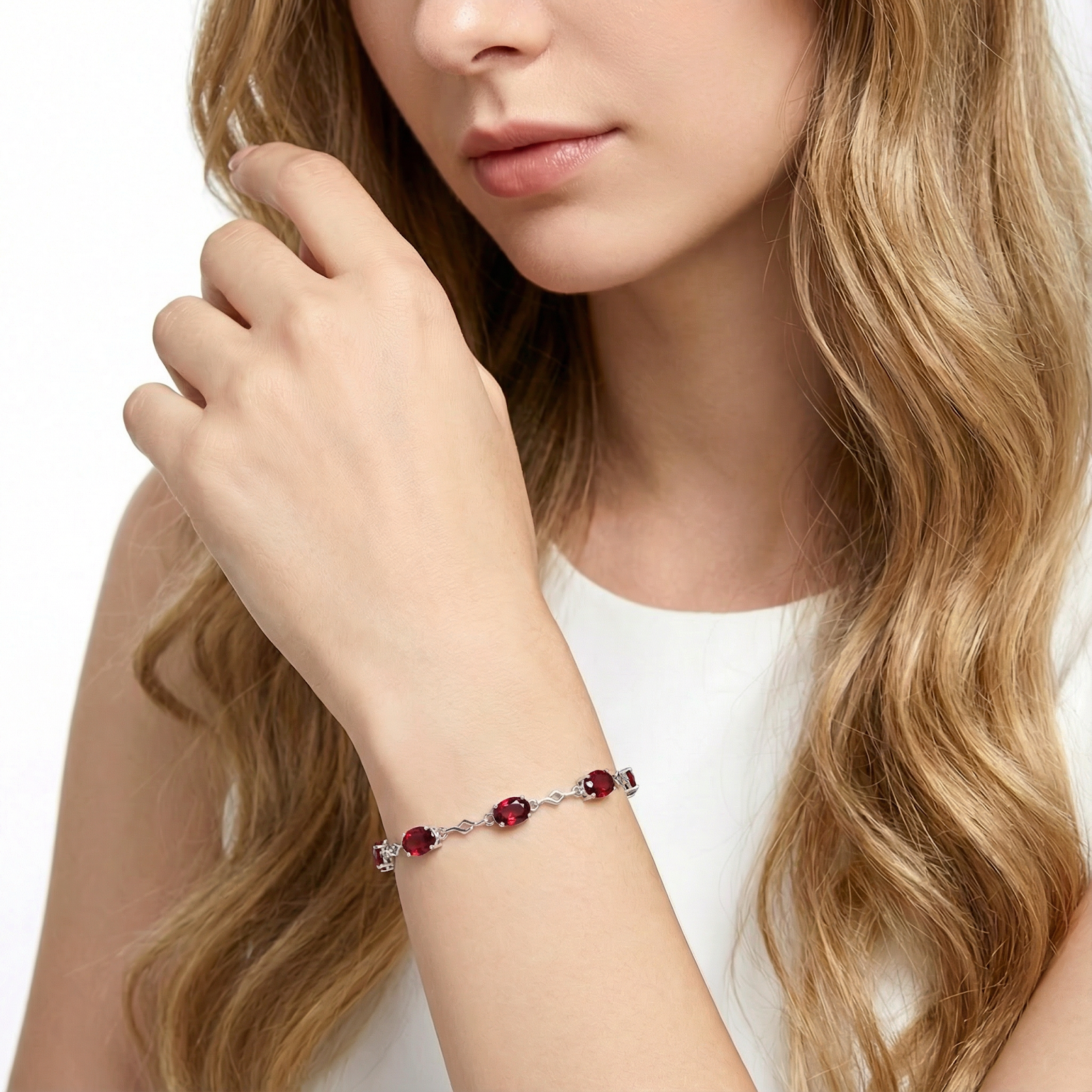 Woman wearing the Thalira sterling silver station bracelet with oval-cut red simulated rubies on her wrist.