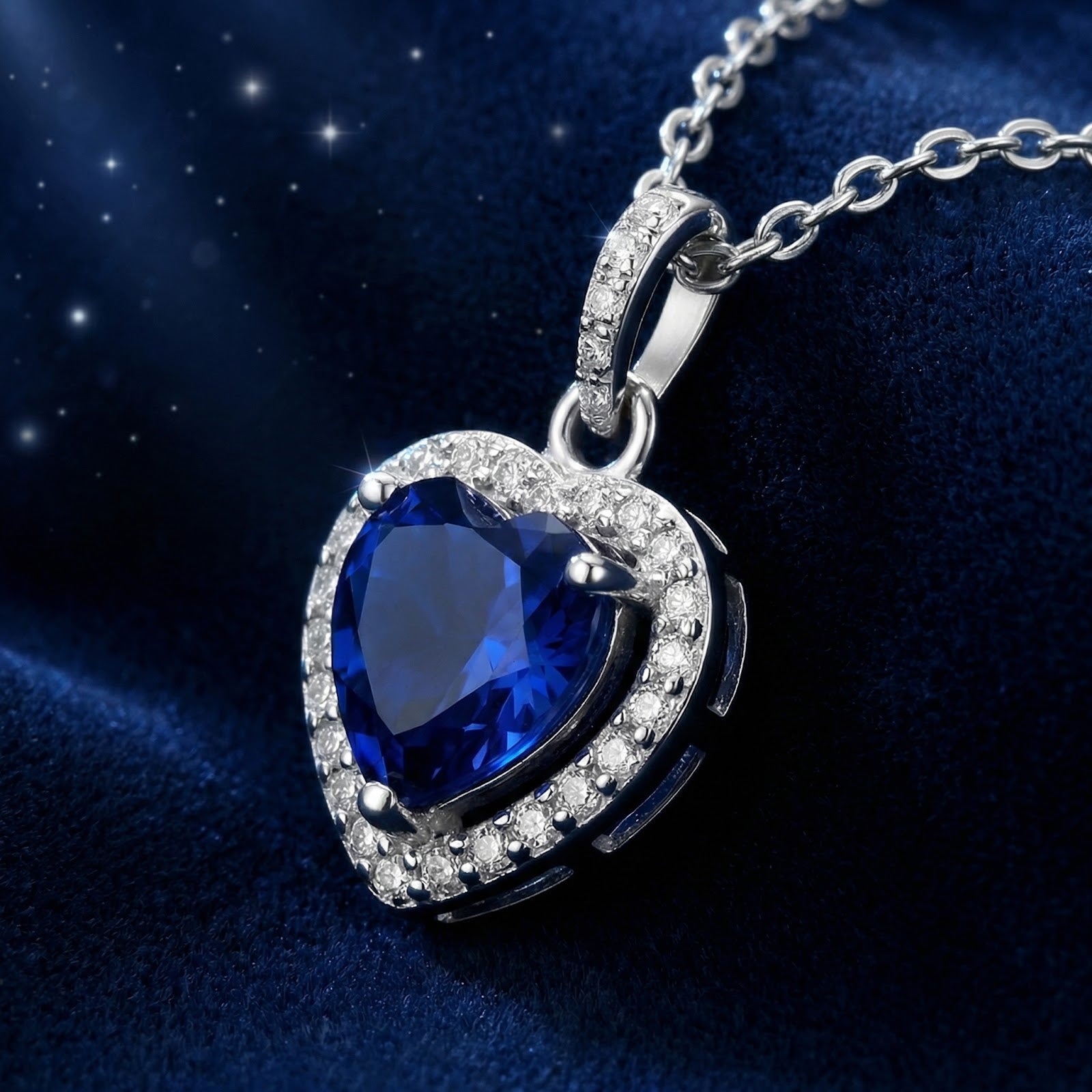 Side-angled macro of the heart-shaped simulated sapphire pendant and sterling silver halo setting on blue velvet.