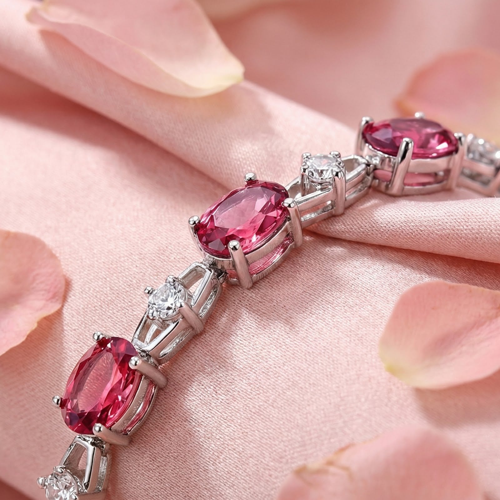 Macro view of oval-cut simulated pink tourmaline stones and silver leaf links on a sterling silver bracelet.