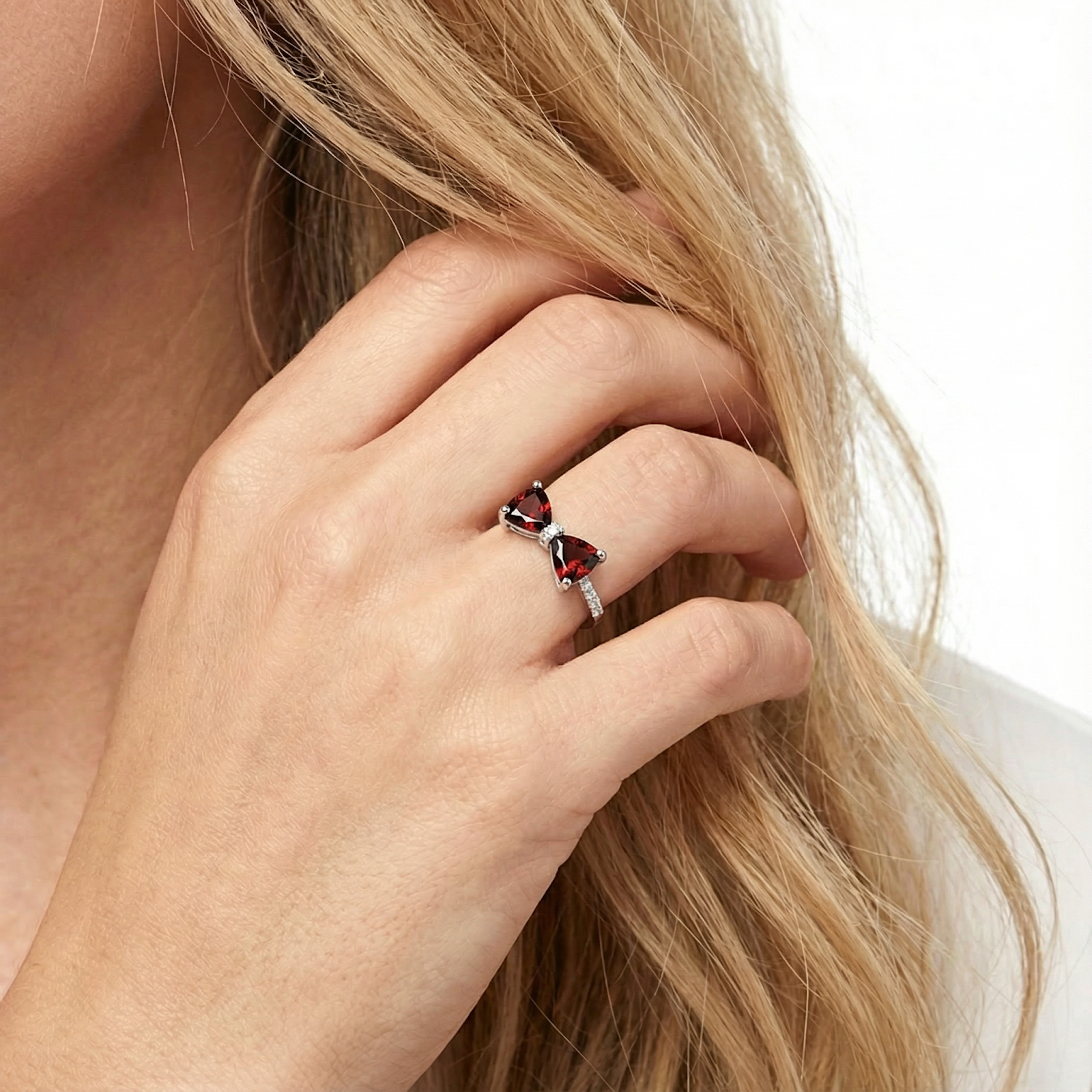 Woman wearing the sterling silver Bellarose bow ring with pigeon blood red simulated garnets.
