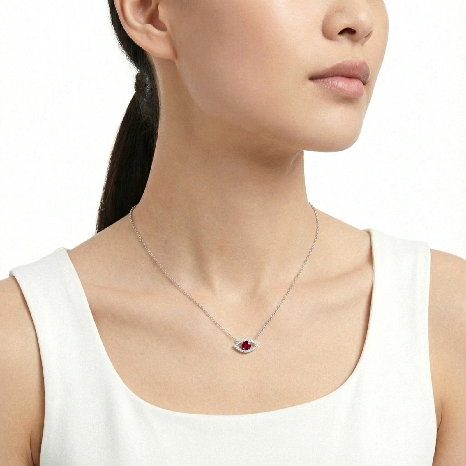 Model wearing the sterling silver Alarice Eye necklace with a red moissanite pendant against a white background.