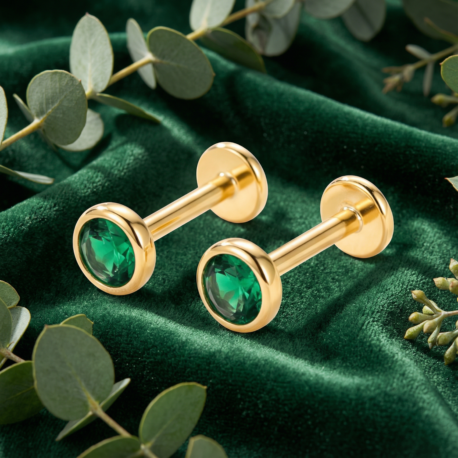 Side view of round simulated emerald bezel stud earrings in 18K gold vermeil on green velvet with flat back posts.