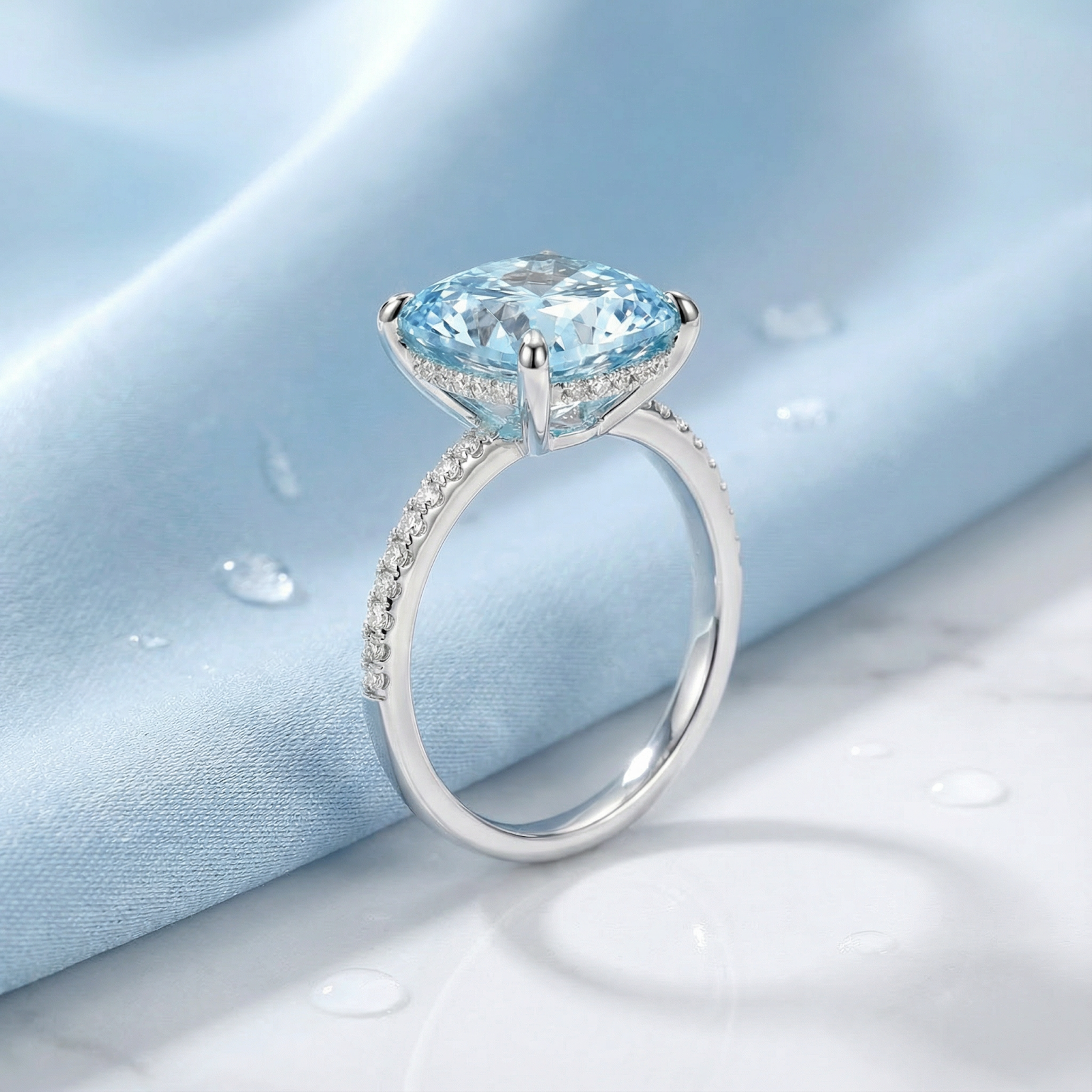 Side view of the Lysia cushion cut simulated aquamarine halo ring in S925 sterling silver on blue fabric.