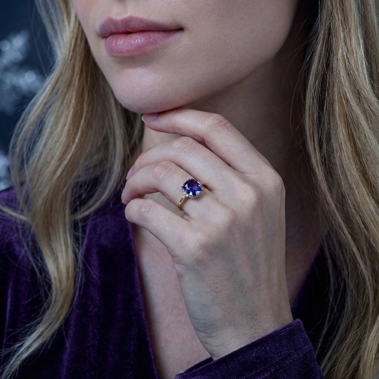 Model wearing the 18K gold vermeil cushion cut simulated tanzanite ring with a purple velvet outfit.