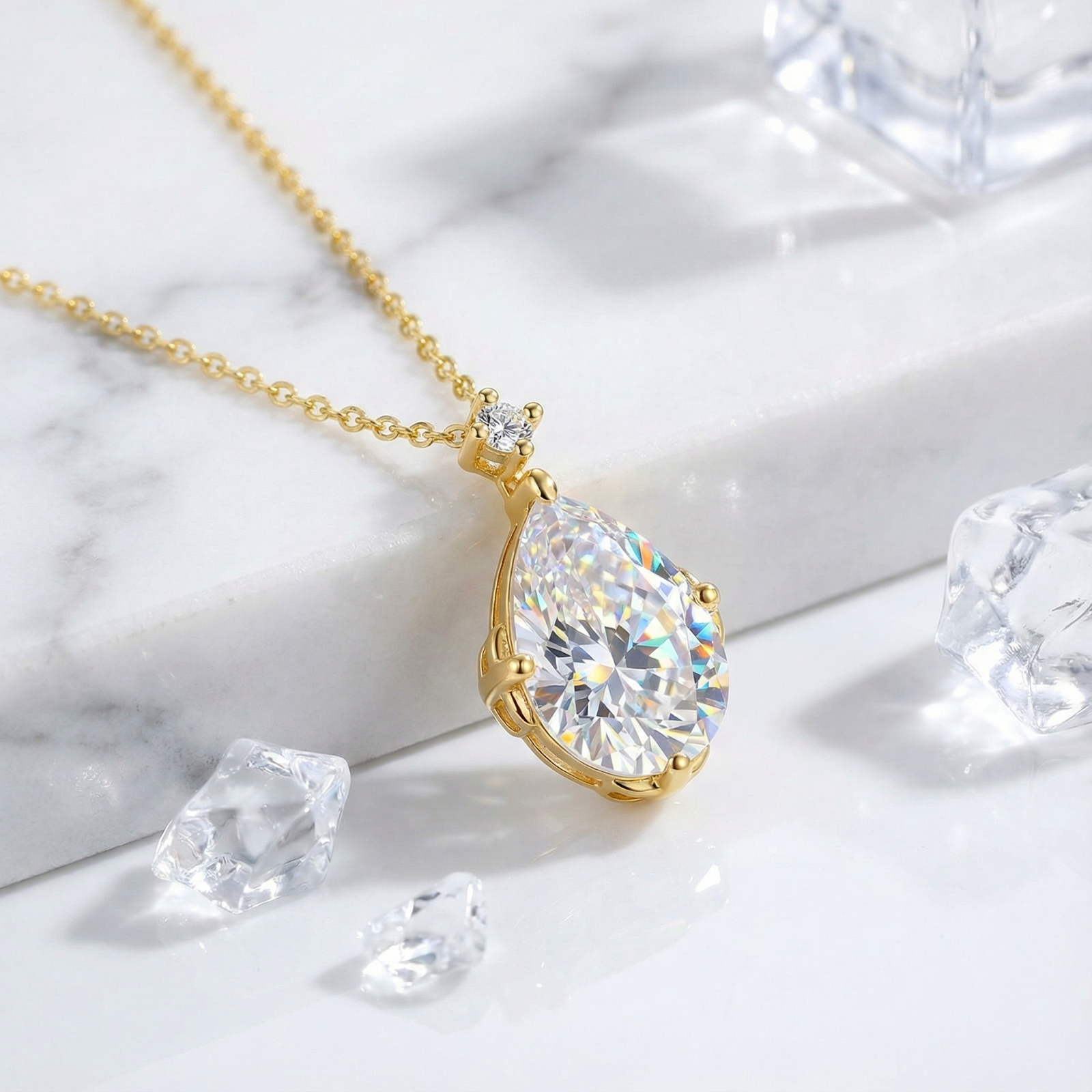 Close-up of a pear-shaped simulated diamond necklace in 18K gold vermeil styled on marble with ice props.