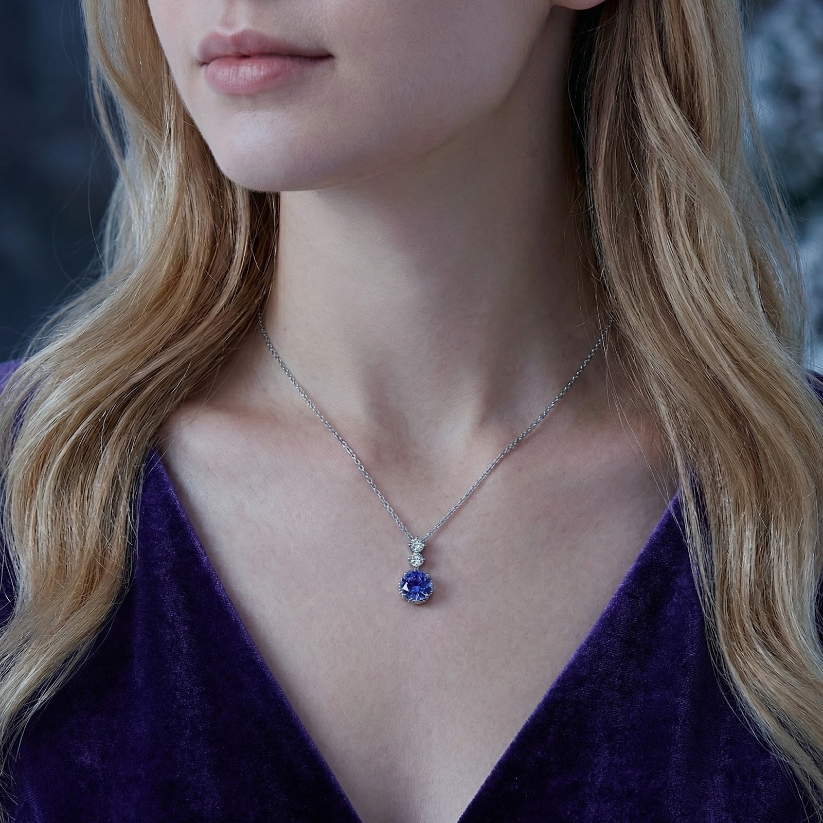 Sterling silver necklace with a round blue simulated tanzanite pendant worn by a model.