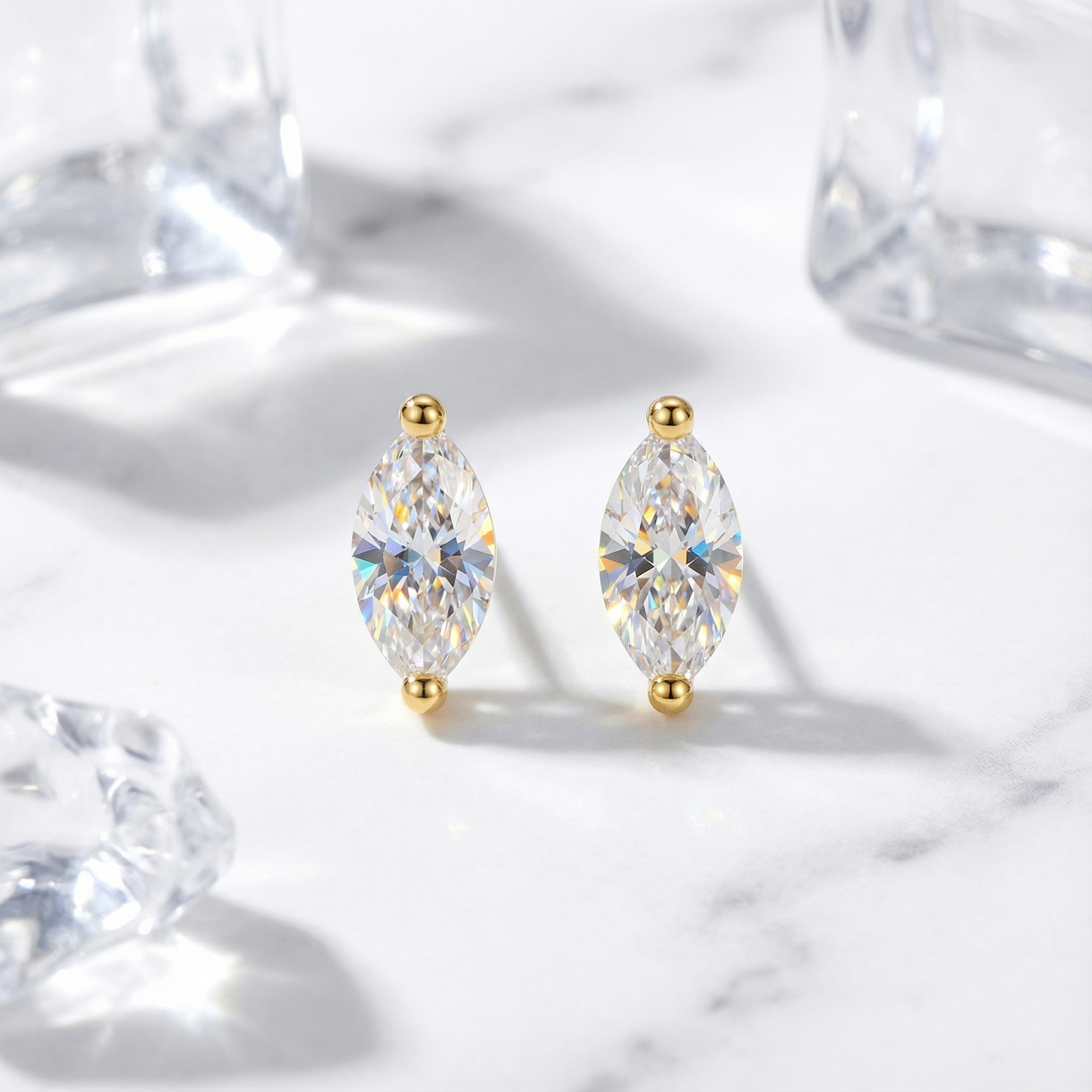 Front view of marquise-cut simulated diamond stud earrings in 18K gold vermeil on a marble background.