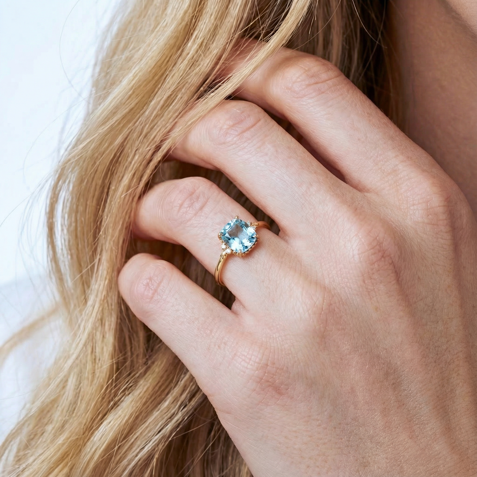 Close-up of the cushion cut simulated aquamarine ring in 18K gold vermeil worn on a model's hand.