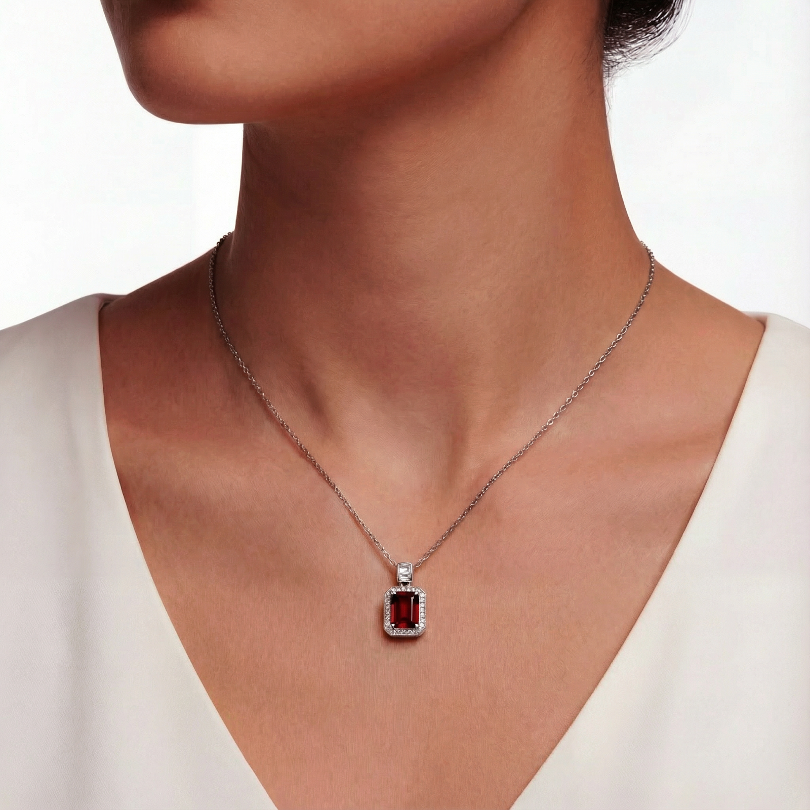 Model wearing the emerald-cut simulated garnet sterling silver necklace with a white top.