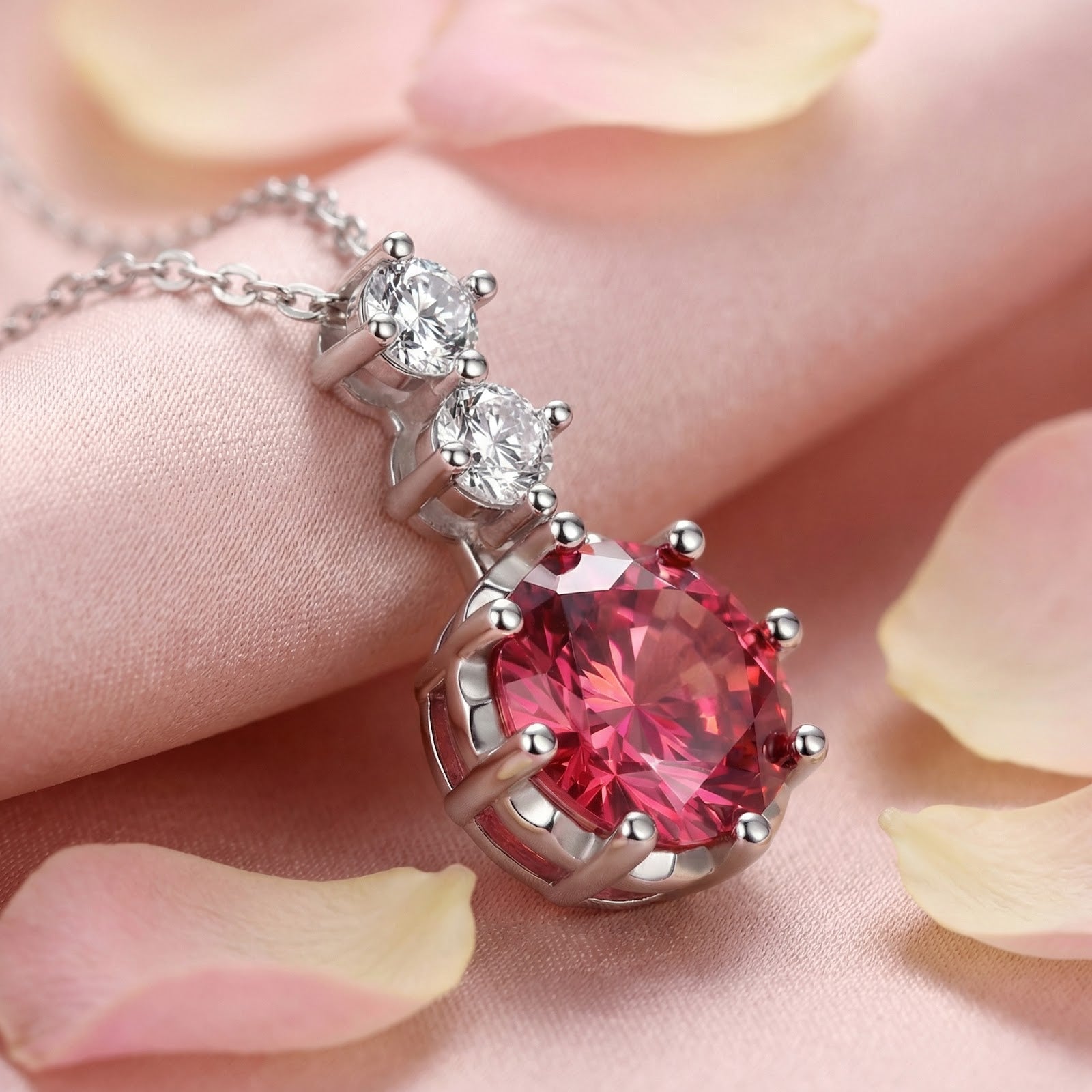 Round-cut pink tourmaline pendant in sterling silver on pink silk with rose petals.