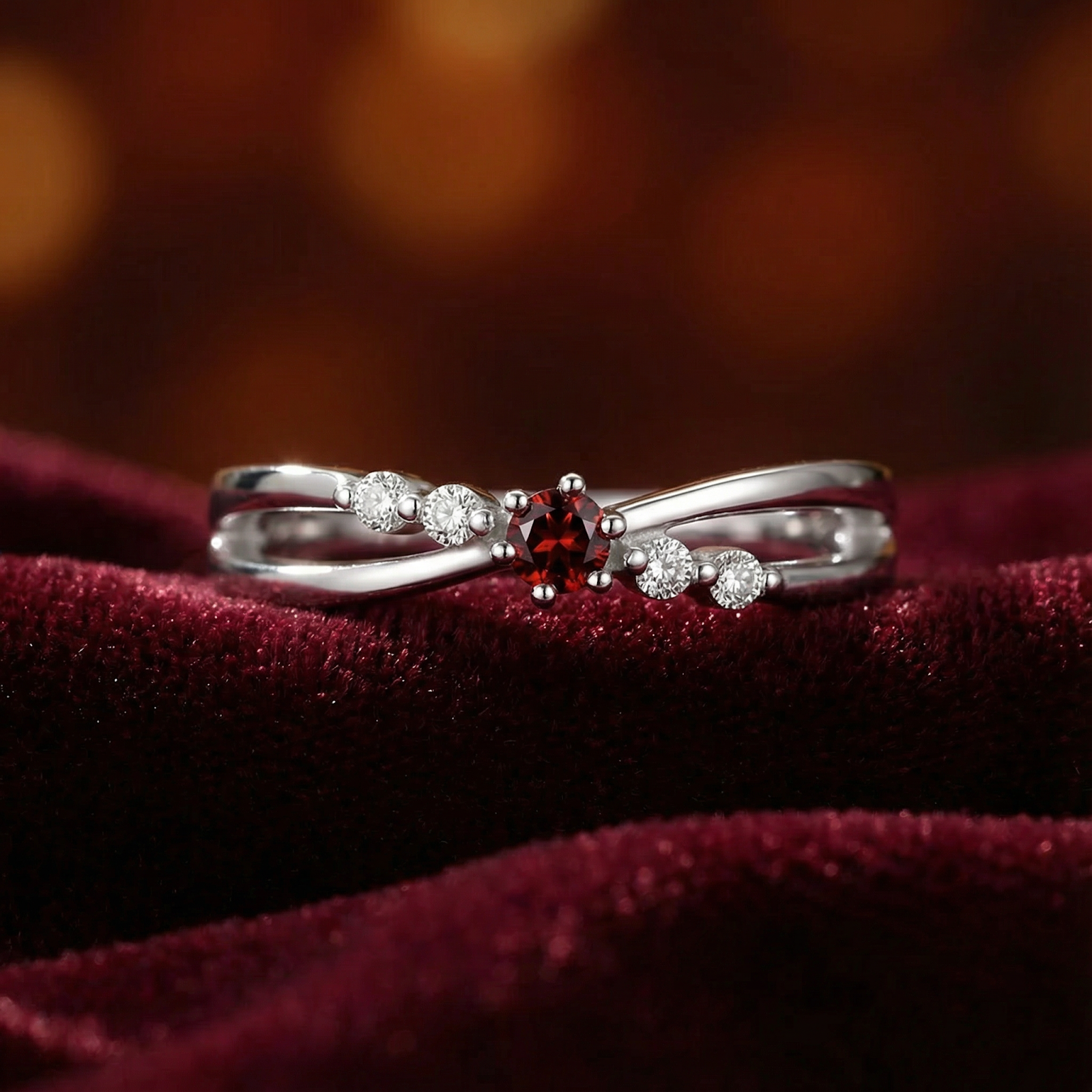 Sterling silver bypass ring with a round simulated garnet on a red velvet background.