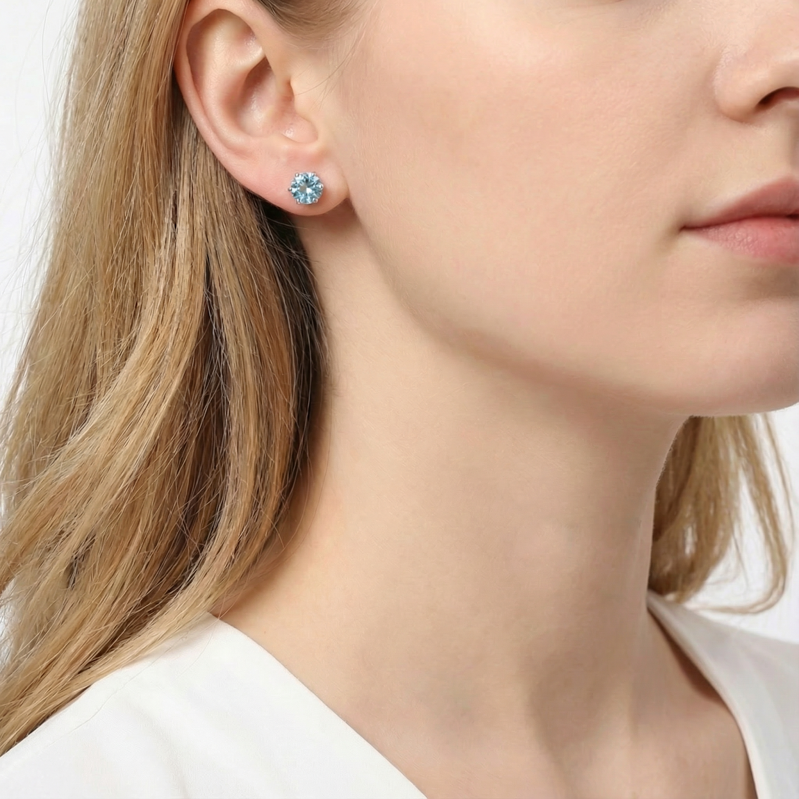 A model wearing the round cut simulated aquamarine stud earring in S925 sterling silver for scale.