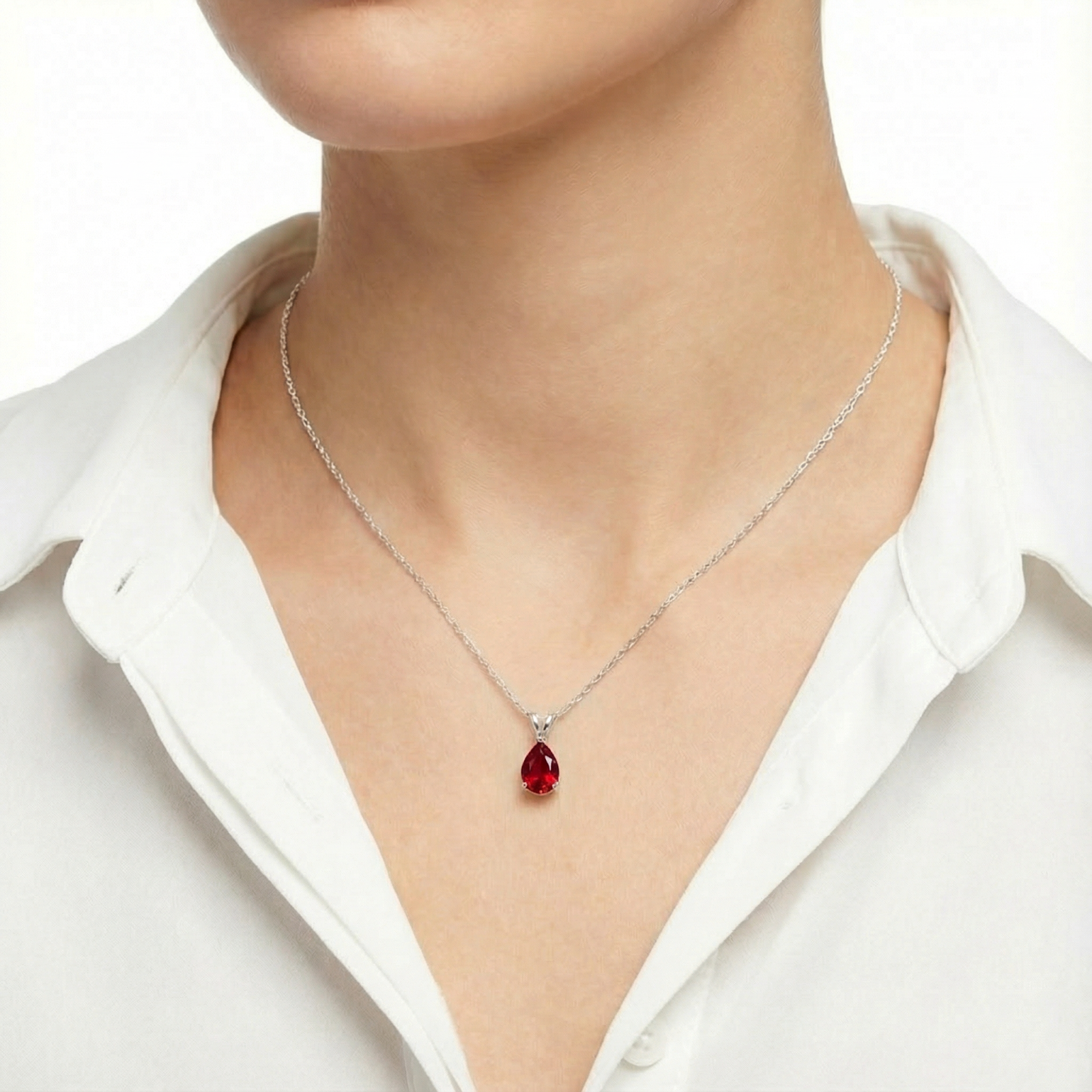 Model wearing the pear cut red moissanite necklace in sterling silver with a white button-down shirt.