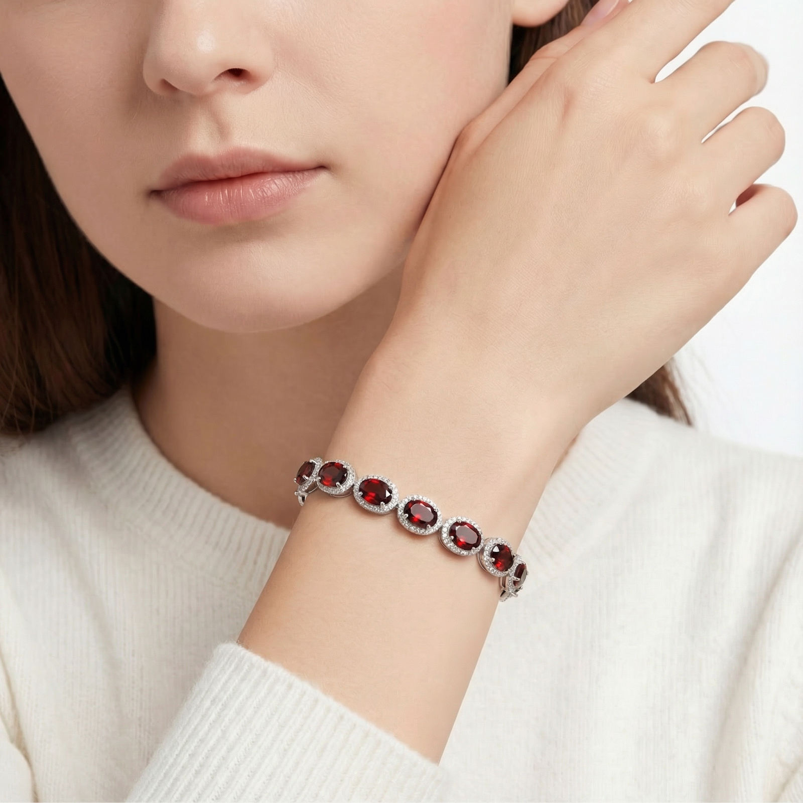 Woman wearing the Cassia halo bracelet in sterling silver with oval simulated garnets on her wrist.