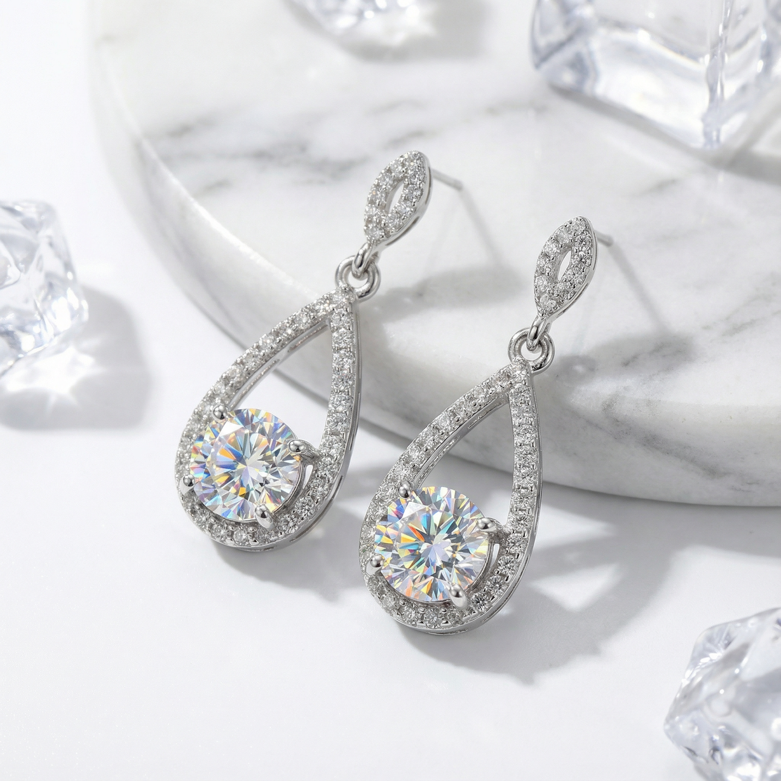 Close-up of sterling silver teardrop earrings featuring brilliant round-cut zirconia and pavé stone settings.