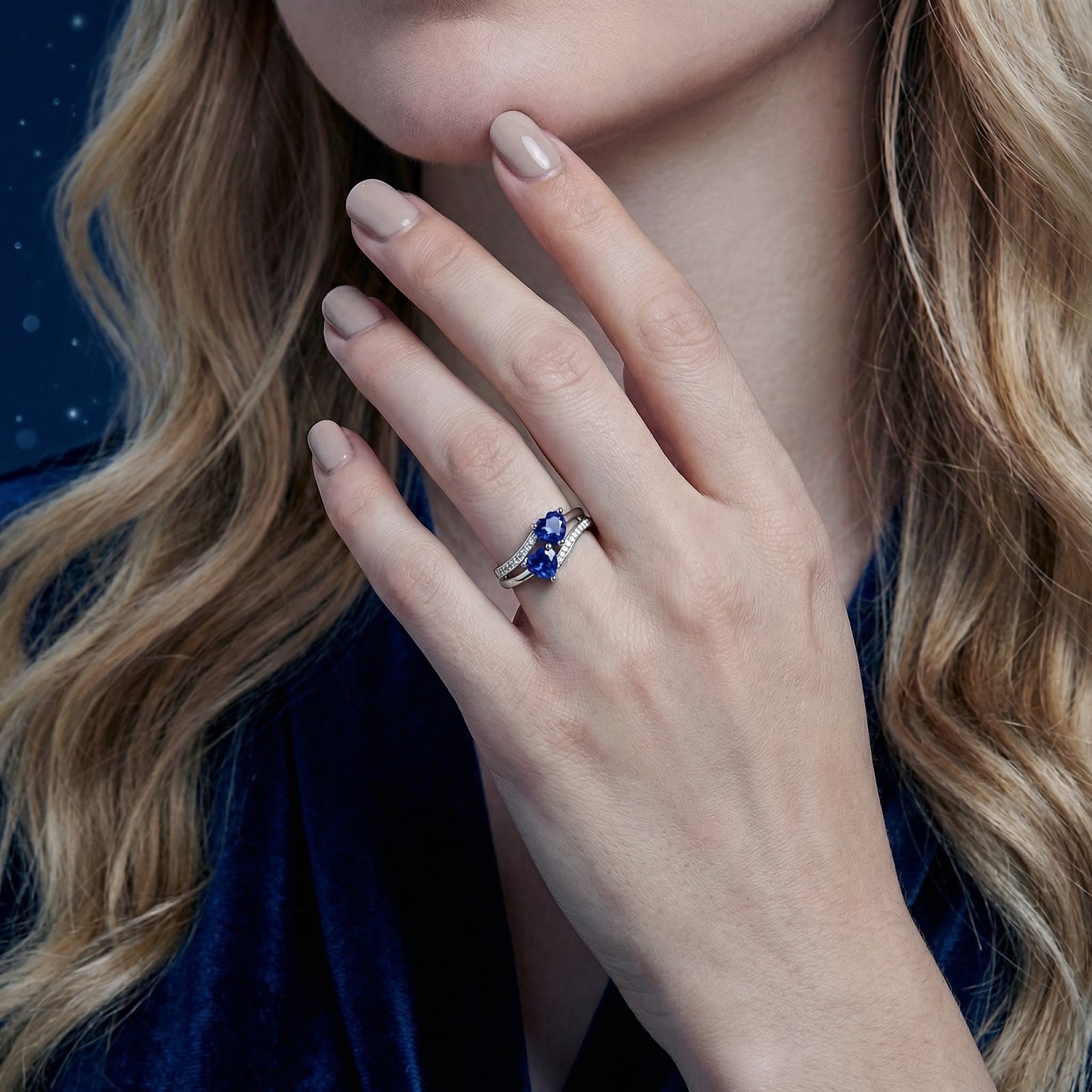 Model wearing the sterling silver heart ring with blue simulated sapphires on her ring finger.