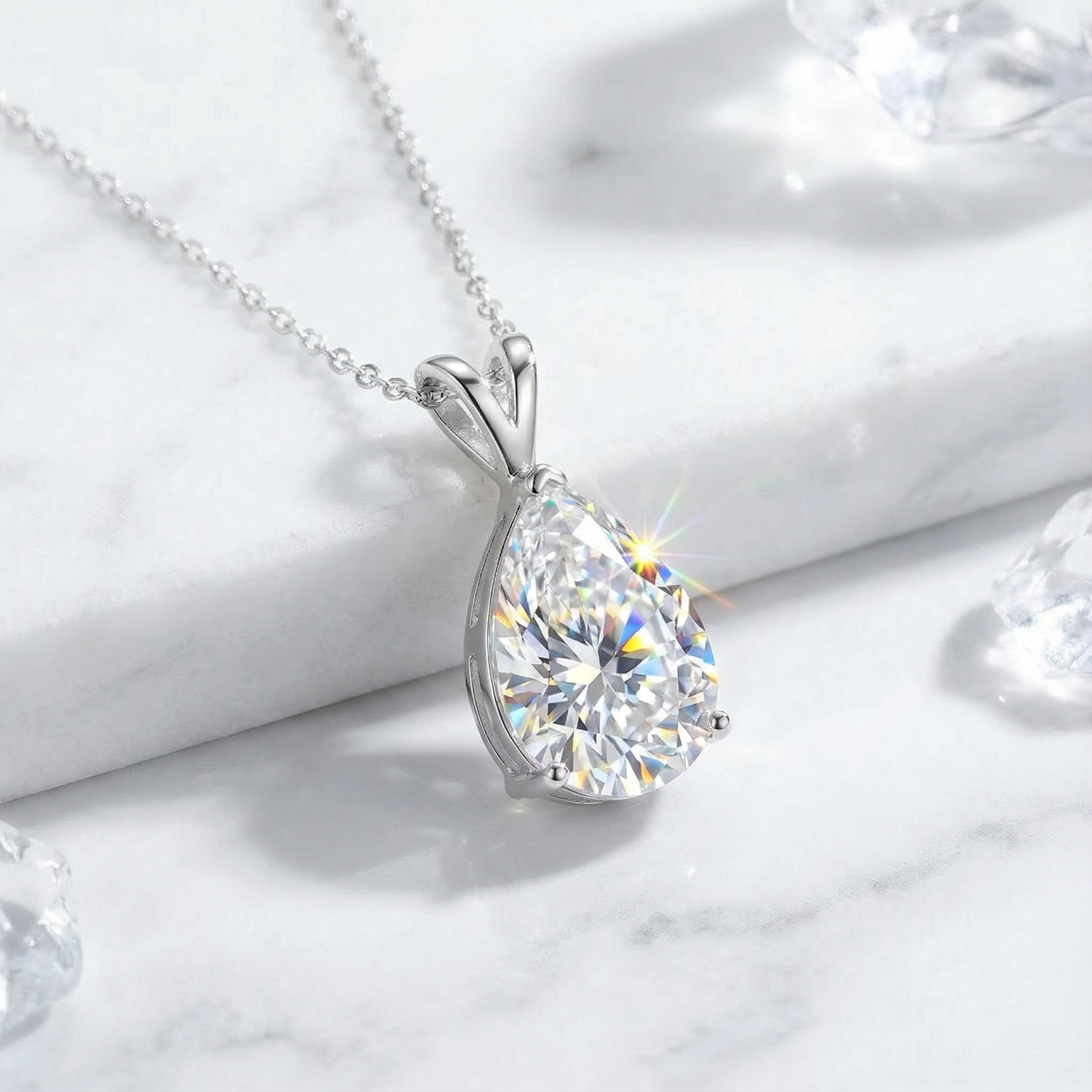 Pear-cut moissanite necklace in S925 sterling silver on a white marble surface with decorative ice crystals.
