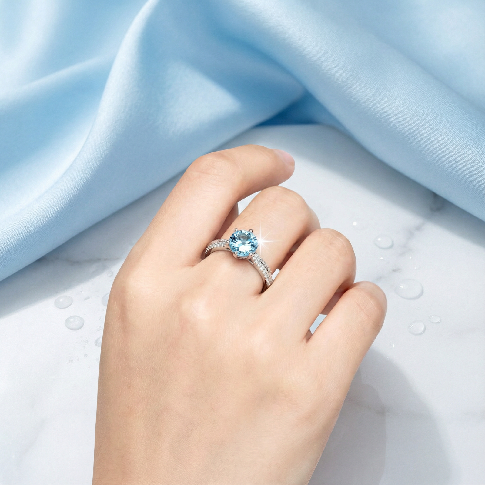Round cut light blue simulated aquamarine solitaire ring in sterling silver worn on a hand for scale.