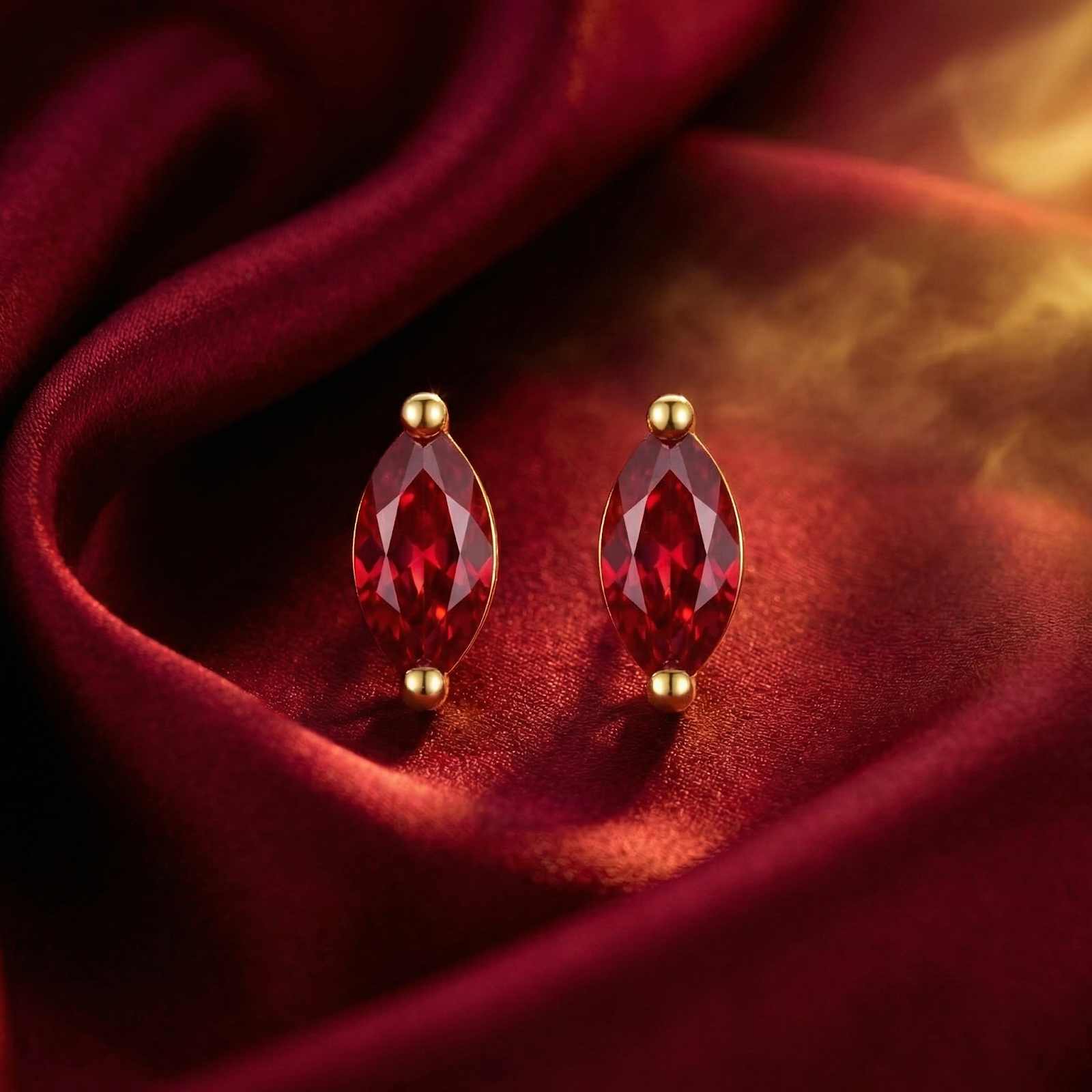 Front view of marquise cut simulated ruby stud earrings in 18K gold vermeil on a red satin background.