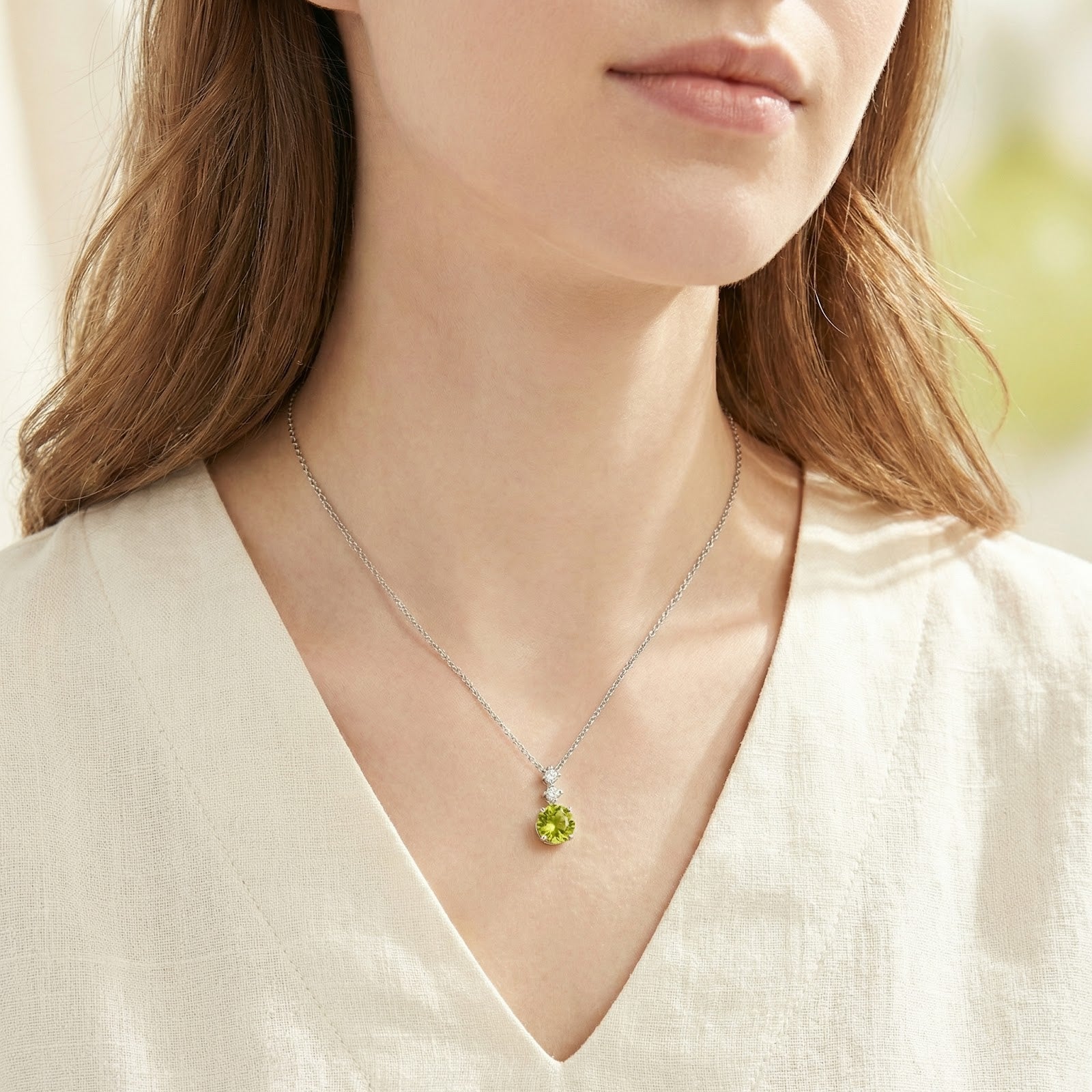 Woman wearing the round-cut simulated peridot necklace in S925 sterling silver on a delicate chain.