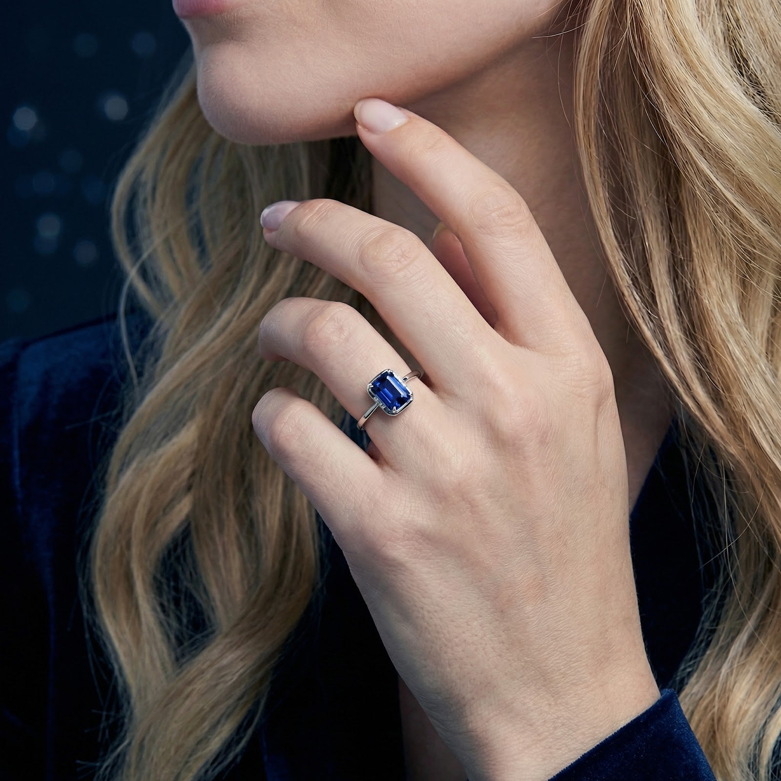 A woman wearing the emerald cut simulated sapphire sterling silver ring, showcasing its size and deep blue color.