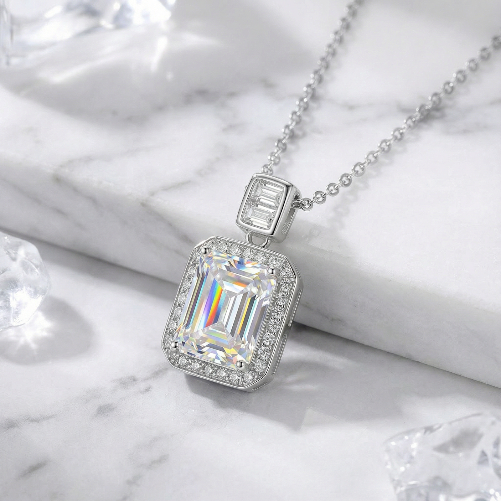 Emerald cut zirconia halo necklace in S925 sterling silver on a white marble surface with crystal accents.
