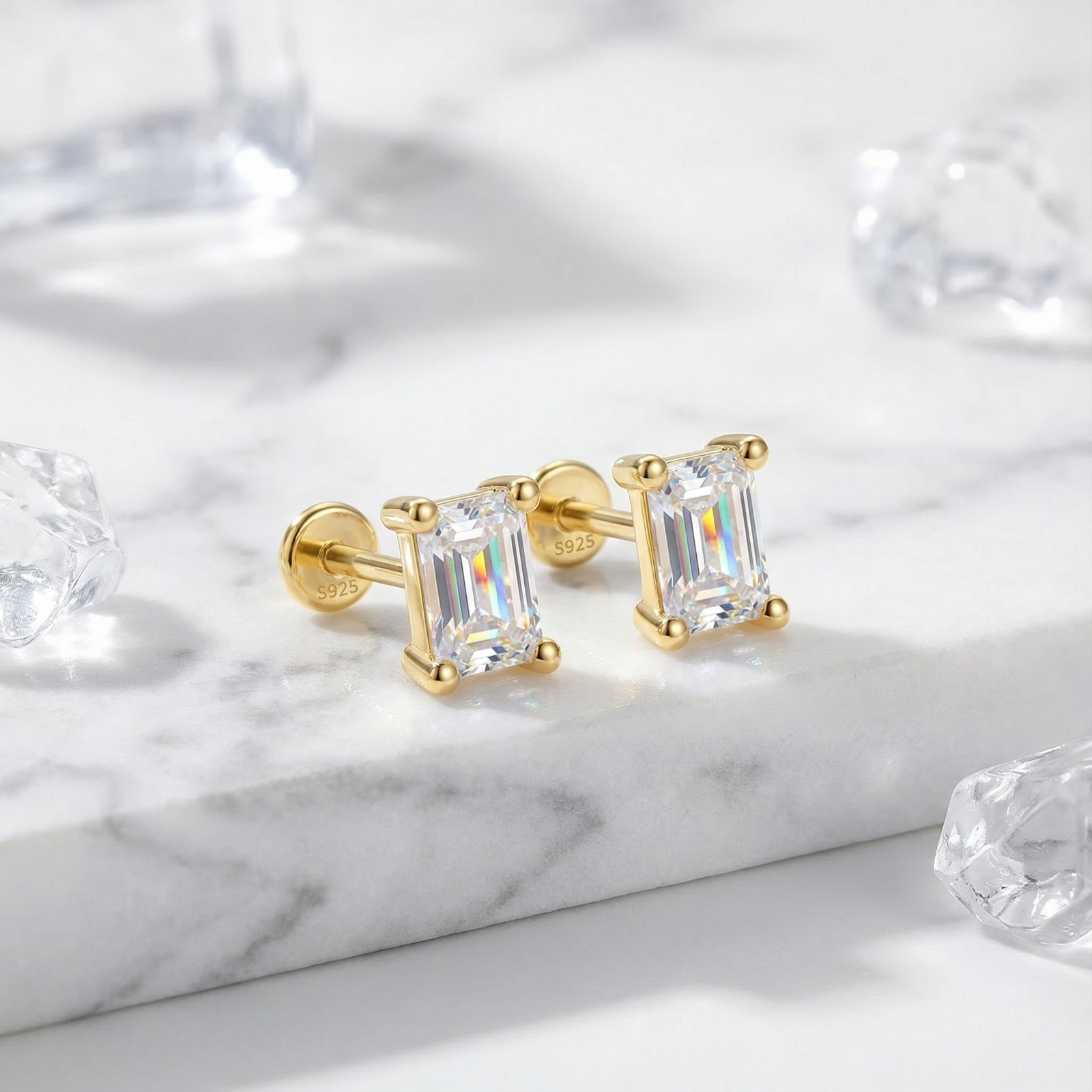 Baguette cut simulated diamond stud earrings in 18K gold vermeil on a white marble surface.