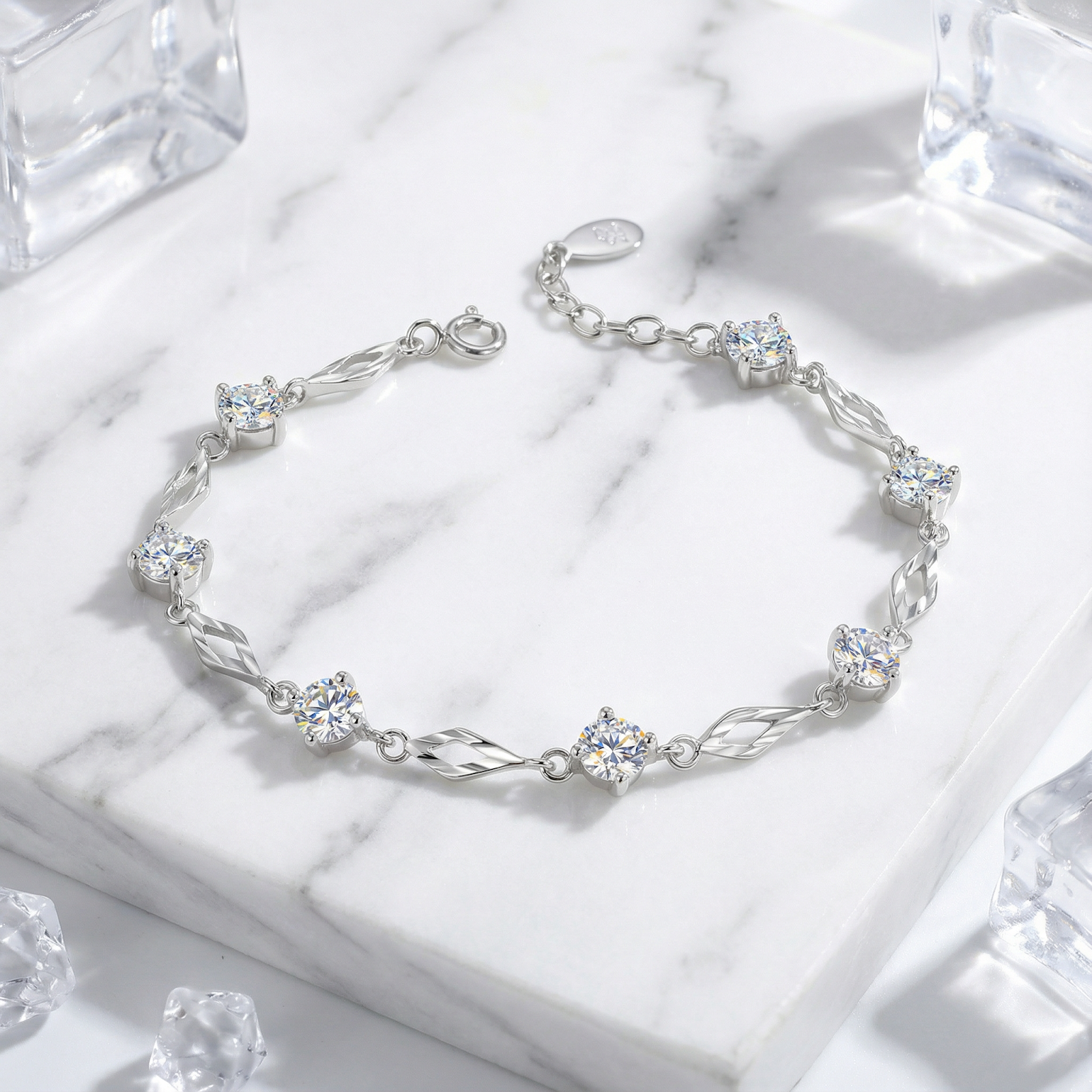Sterling silver station bracelet with round cut simulated diamonds on a white marble surface with decorative ice.