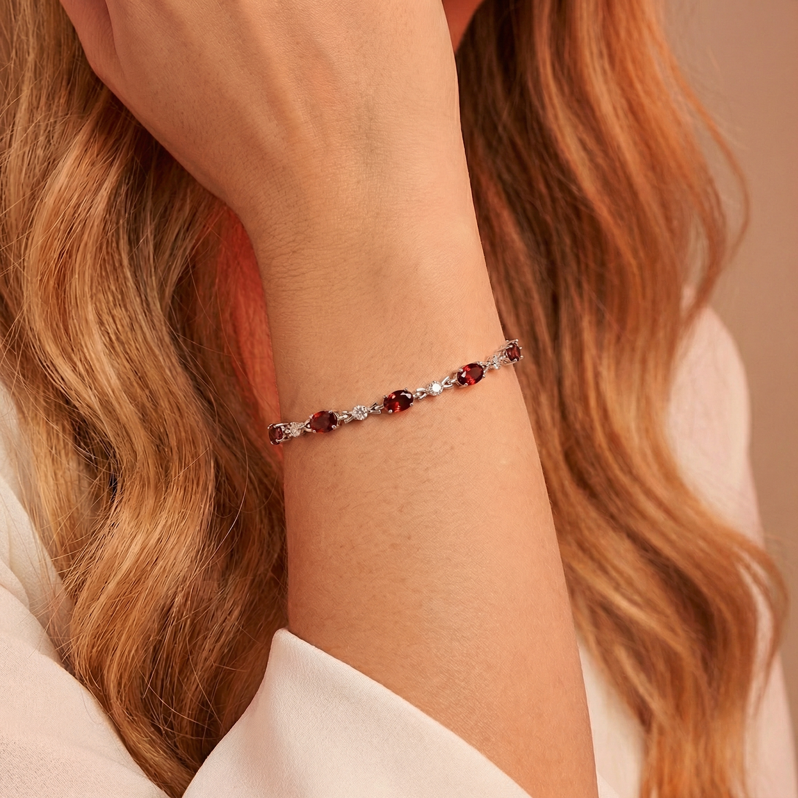 Sterling silver Melora bracelet with oval cut simulated garnets worn on a woman's wrist.