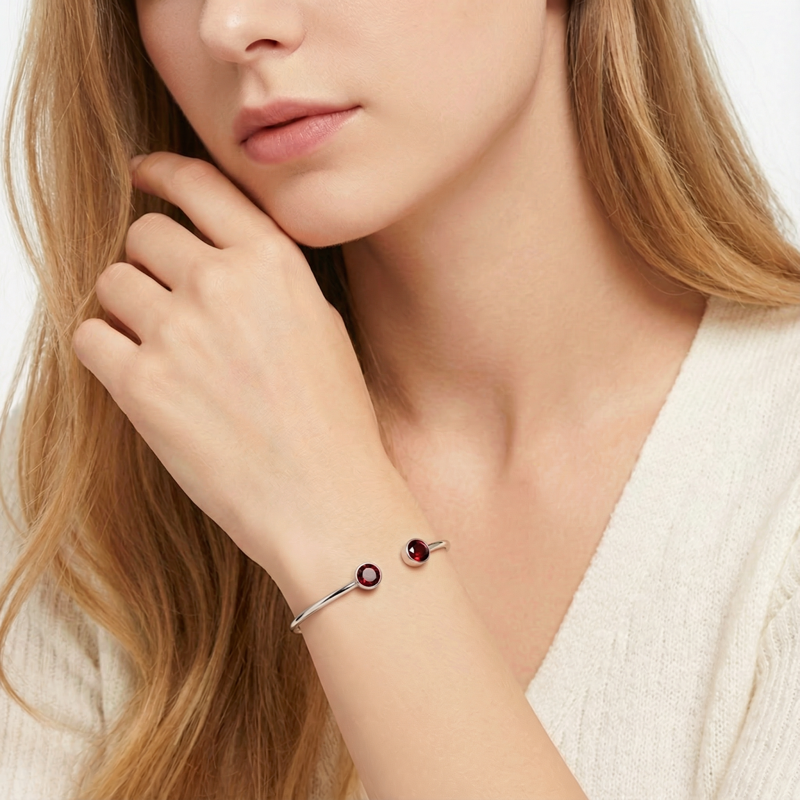 Woman wearing the stainless steel Odyssea cuff bracelet with January birthstone simulated garnets.