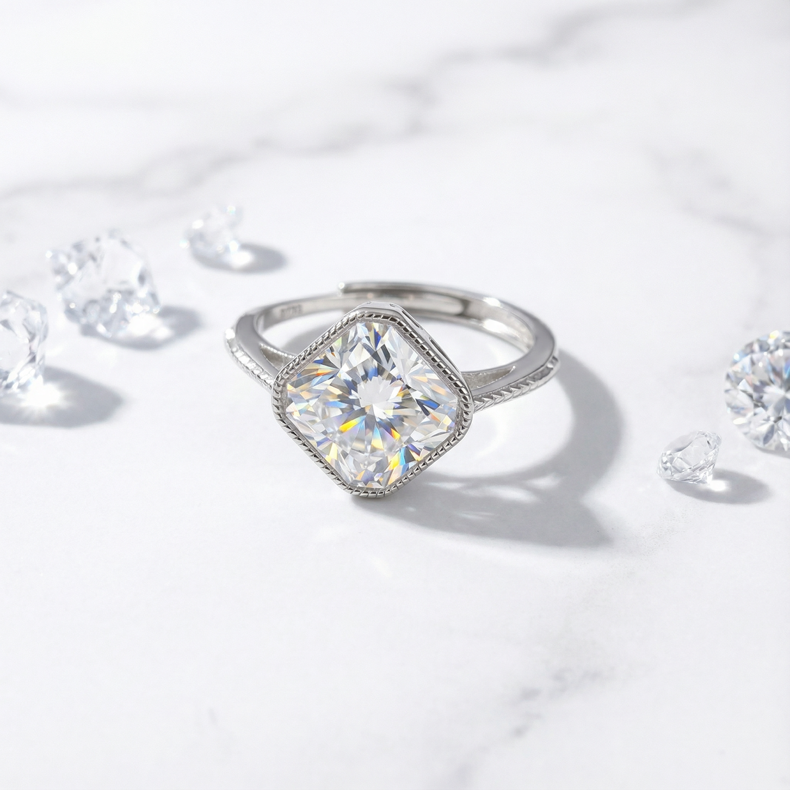 Cushion cut simulated diamond ring in S925 sterling silver on a white marble surface with loose crystals.