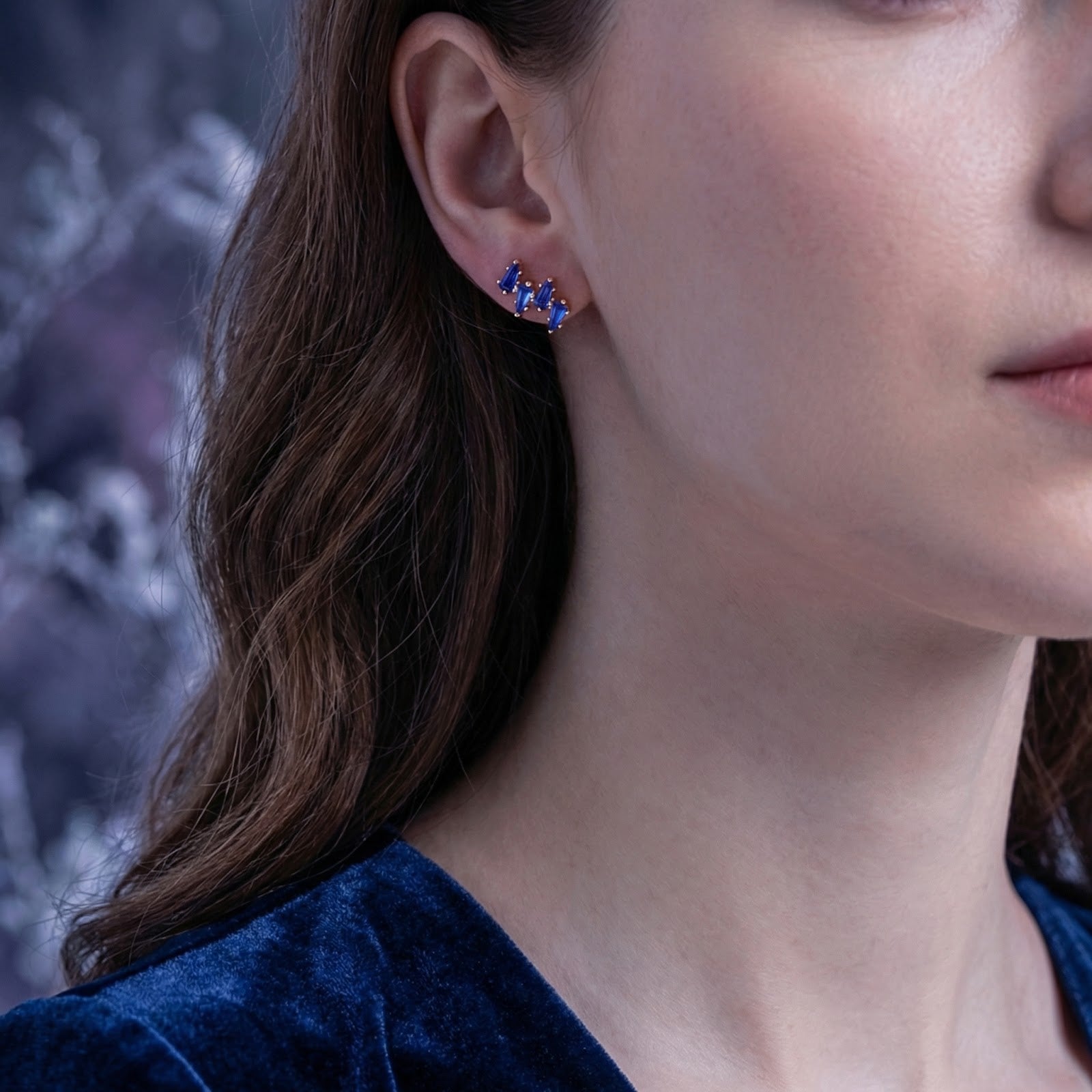 A woman wearing the 18K gold vermeil Neriselle cluster earring featuring blue-violet simulated tanzanite stones.