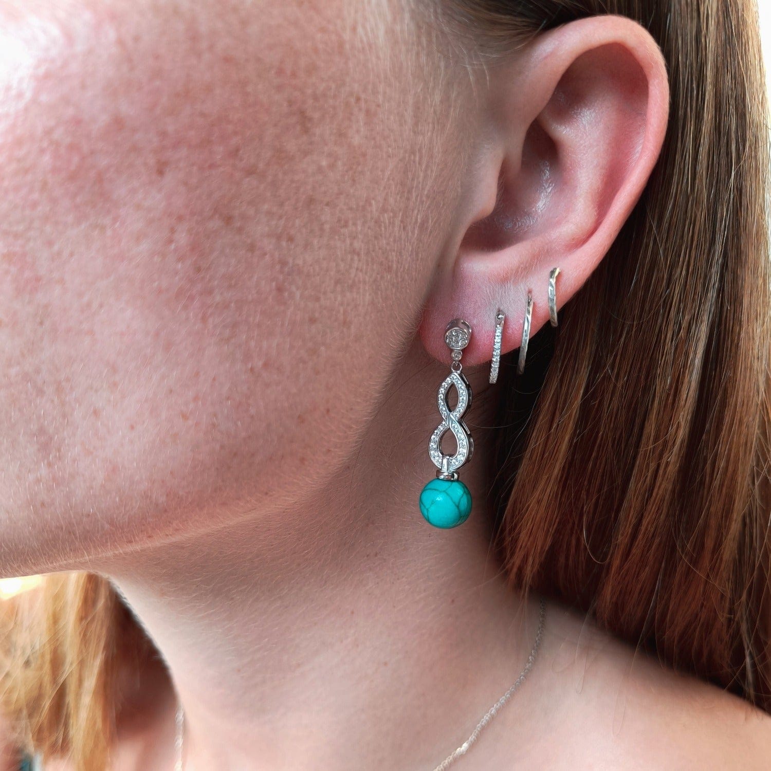 Azure Oceanic Earrings featuring turquoise stones in a sterling silver setting on a model