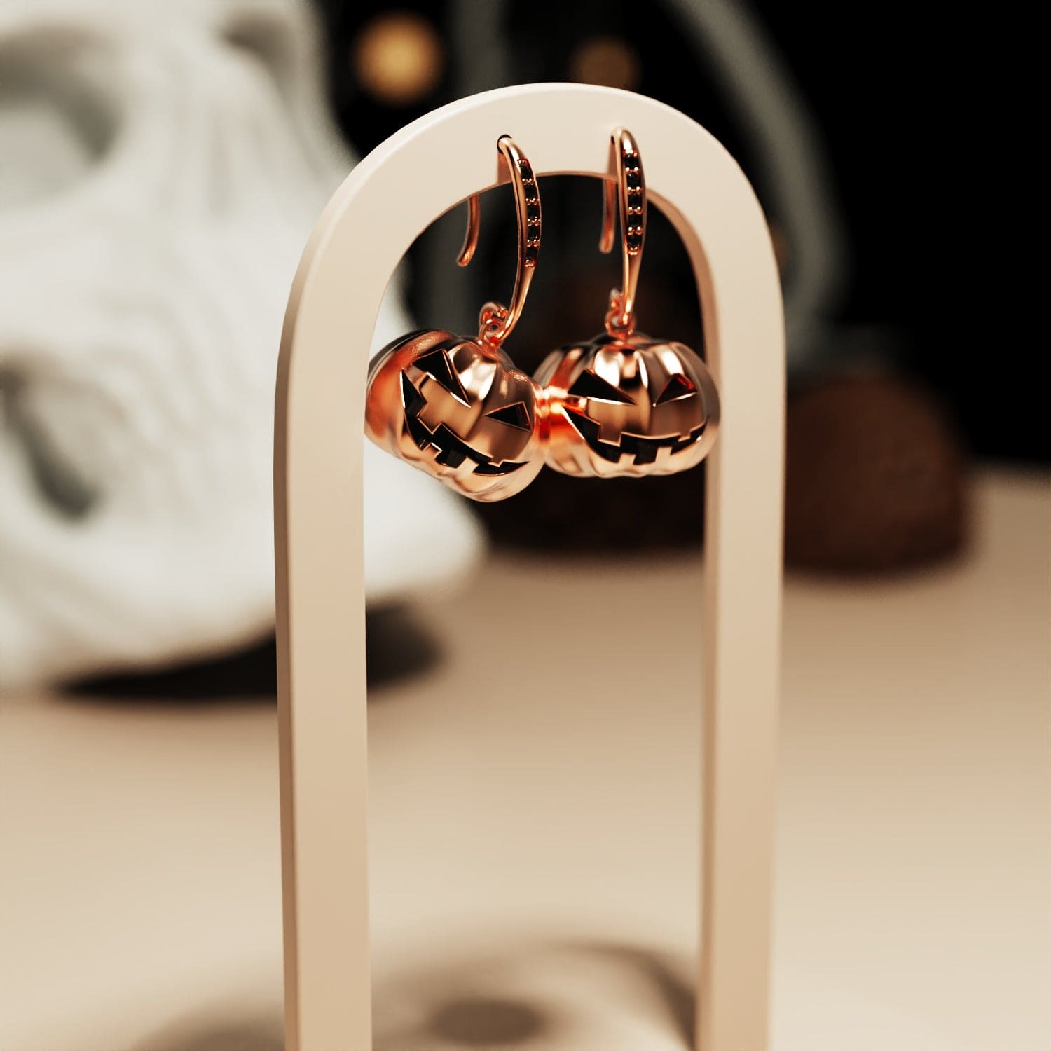 Halloween pumpkin earrings hanging from stand modelled for showcasing with dark black gemstones in a copper color