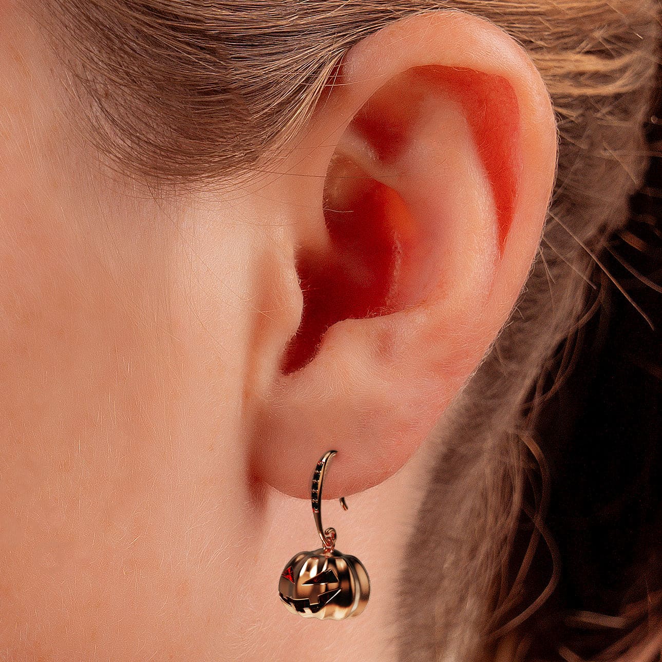 Photo of model wearing halloween pumpkin earrings close up of the ear