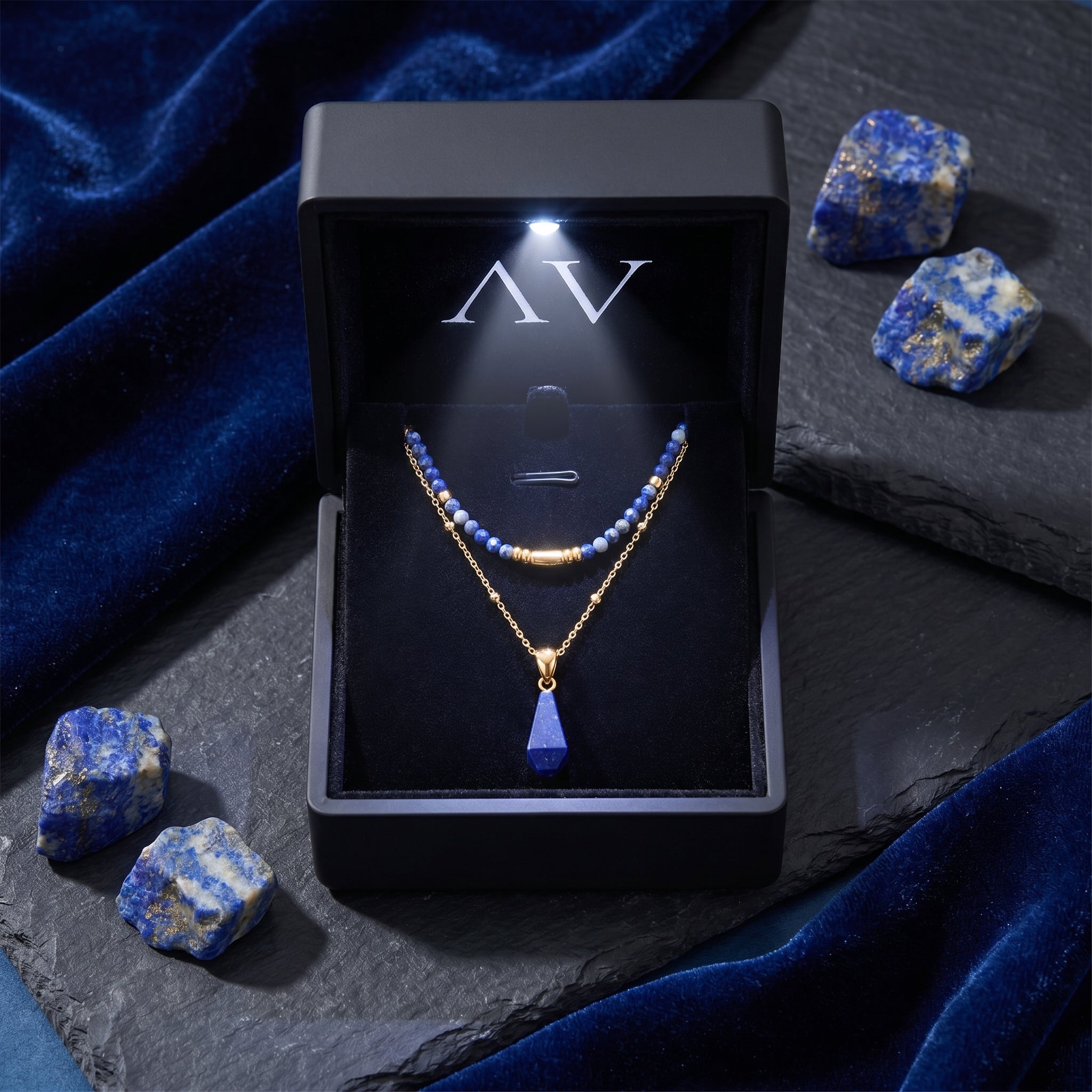 Gold layered lapis necklace displayed in a black lighted gift box with raw lapis stones on the side.