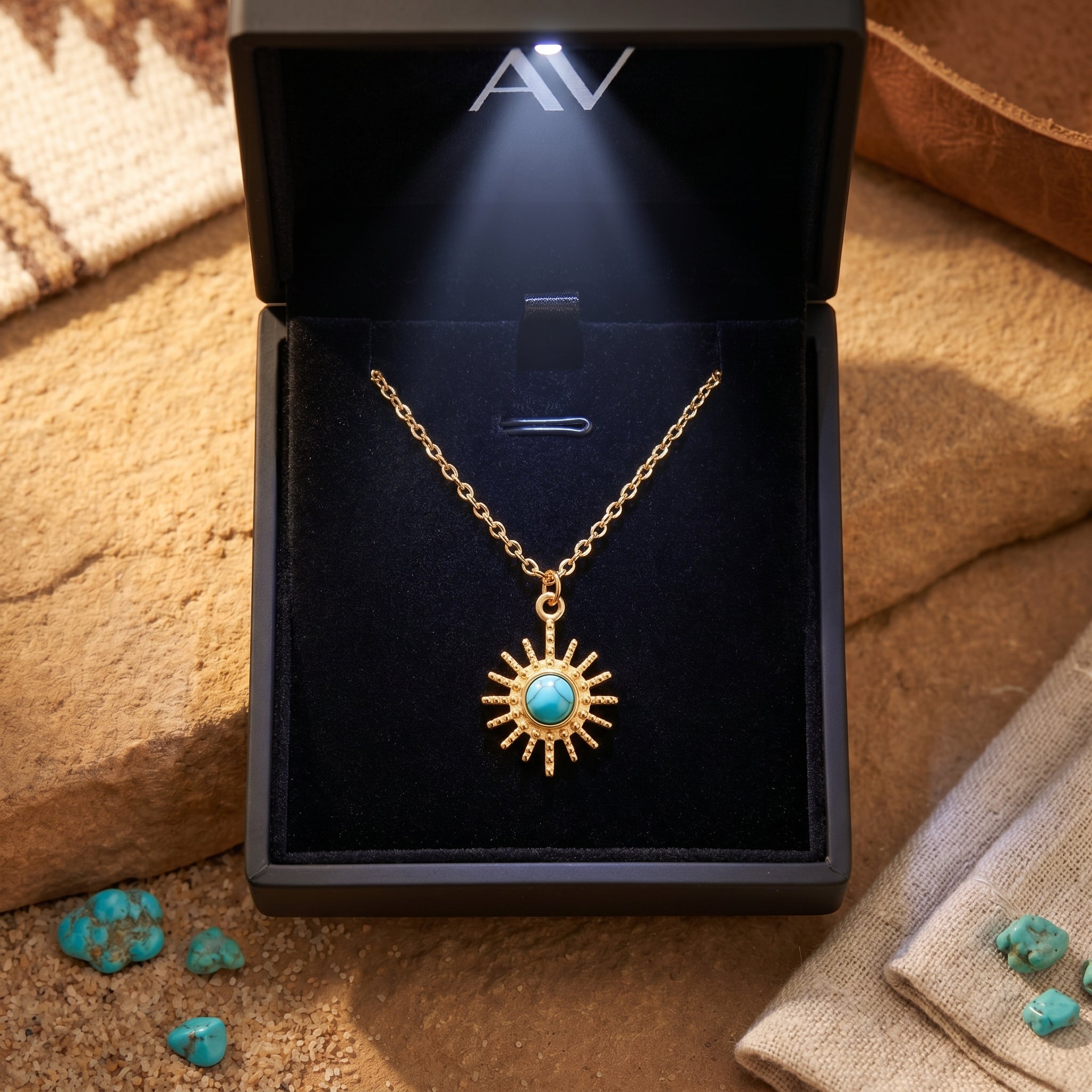 18K gold sunburst turquoise necklace presented in a black LED-lit gift box on a desert background.